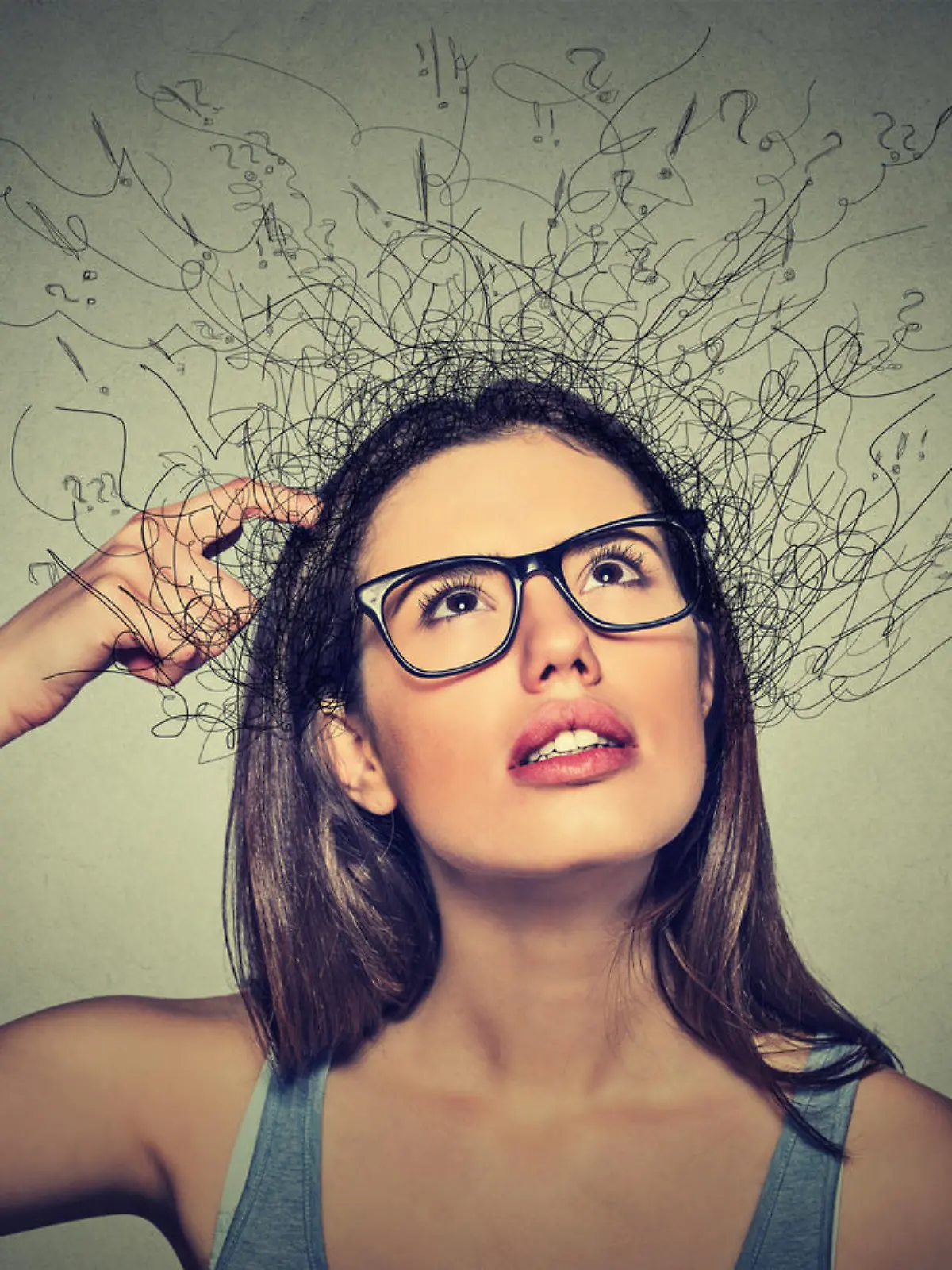 Closeup portrait young woman scratching head, thinking daydreaming with brain melting into lines question marks looking up isolated on gray background. Human facial expressions, emotion feeling sign