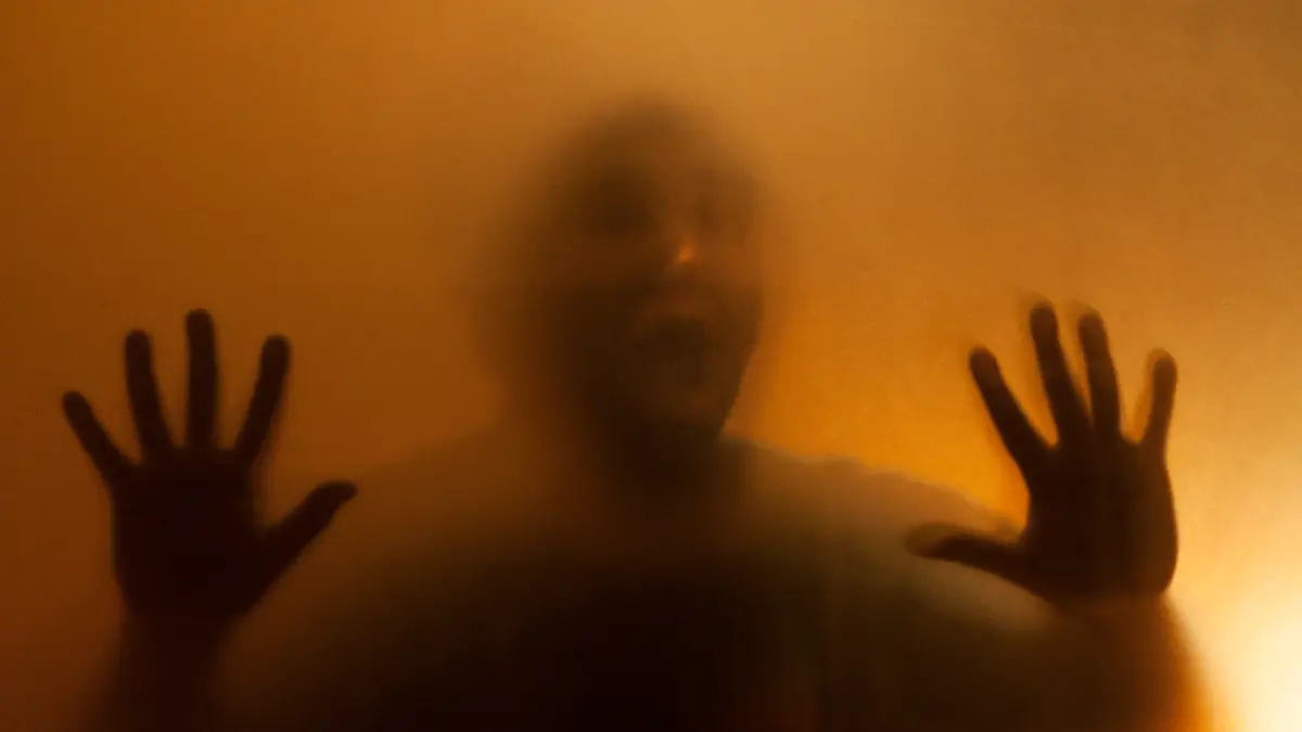 Man screaming with anger behind translucent surface