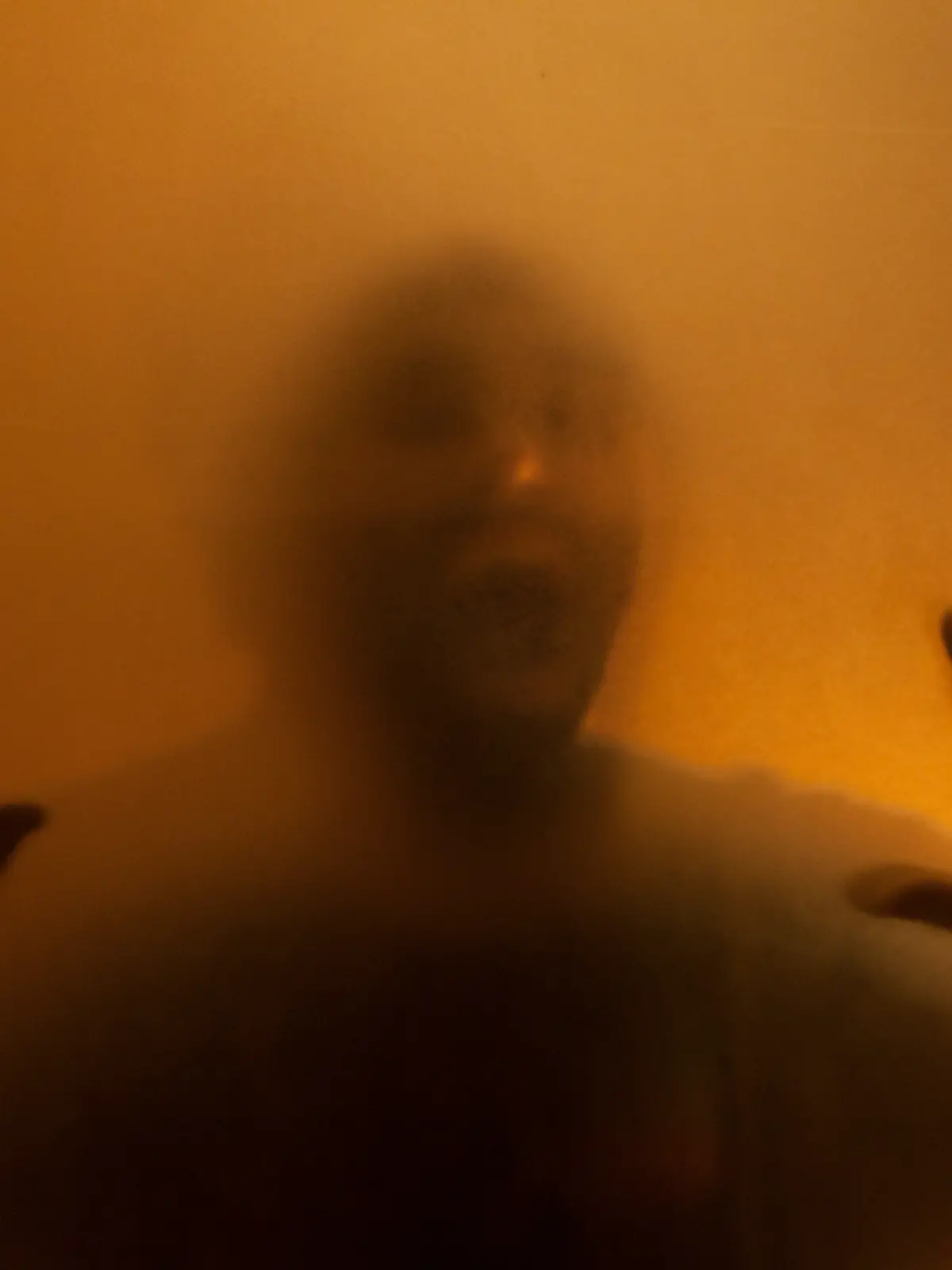 Man screaming with anger behind translucent surface