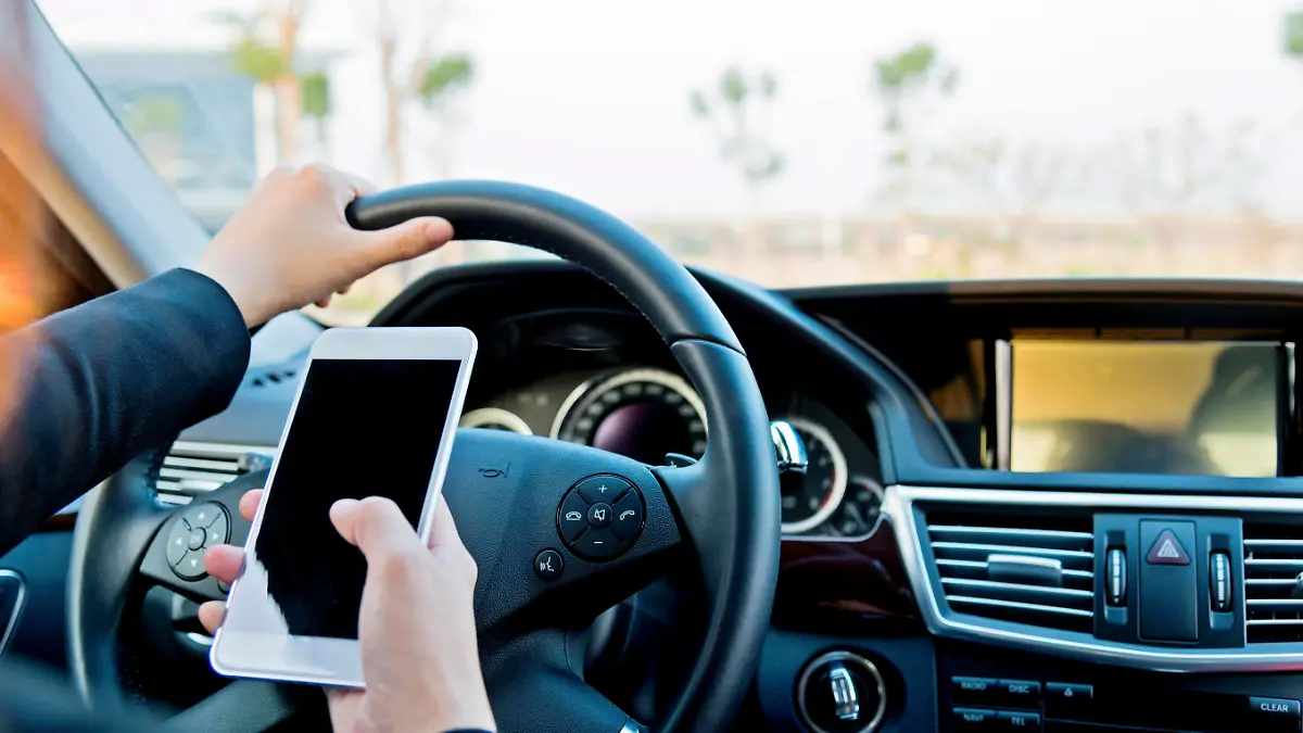 Female driver texting on mobile phone while driving.
