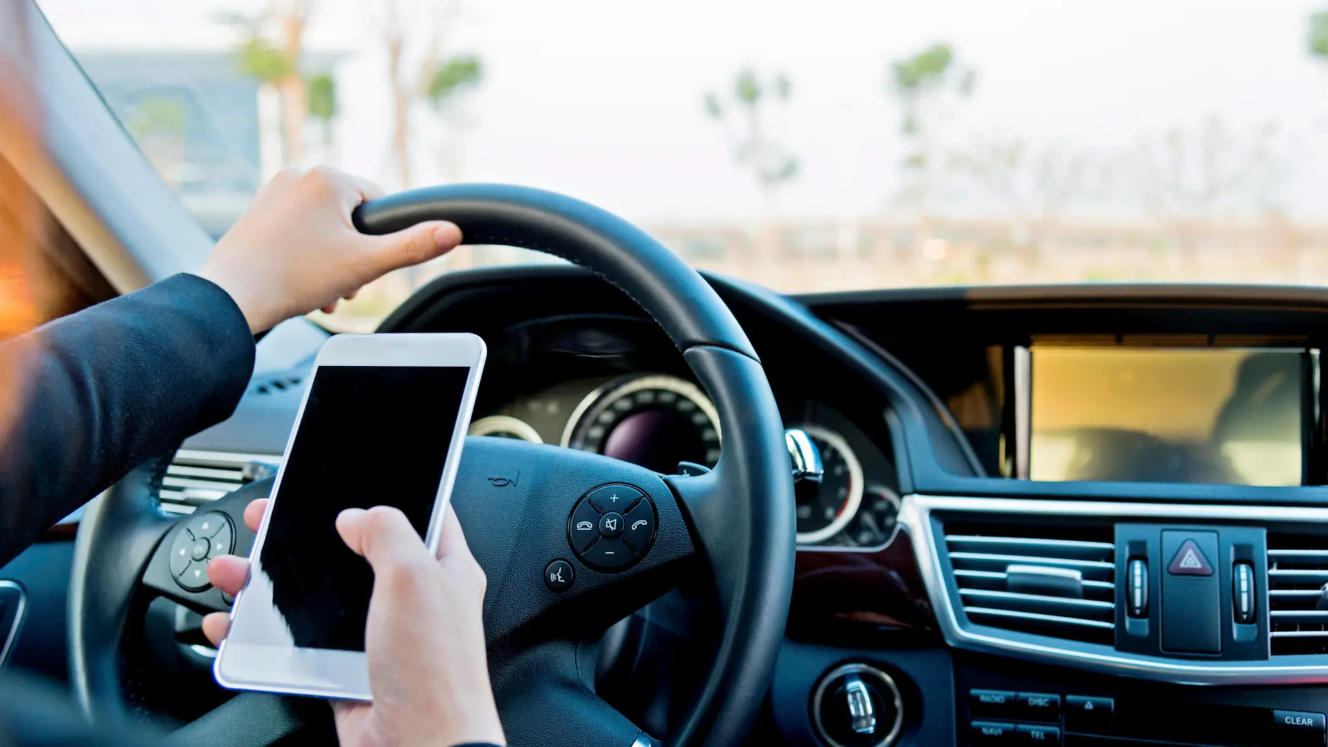 Female driver texting on mobile phone while driving.