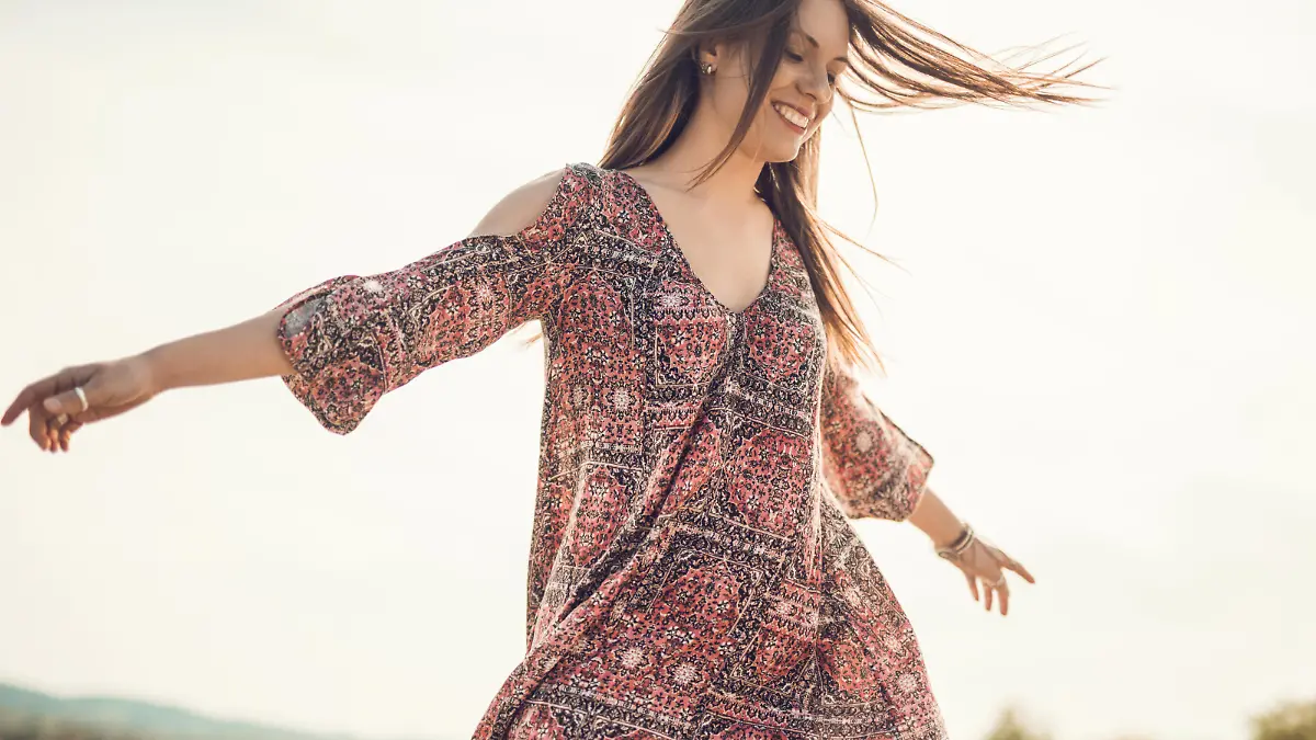 Young happy woman having fun outdoors while spinning with her arms outstretched.
