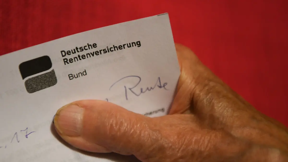 Eine Rentnerin hält ihren Rentenbescheid in der Hand.
