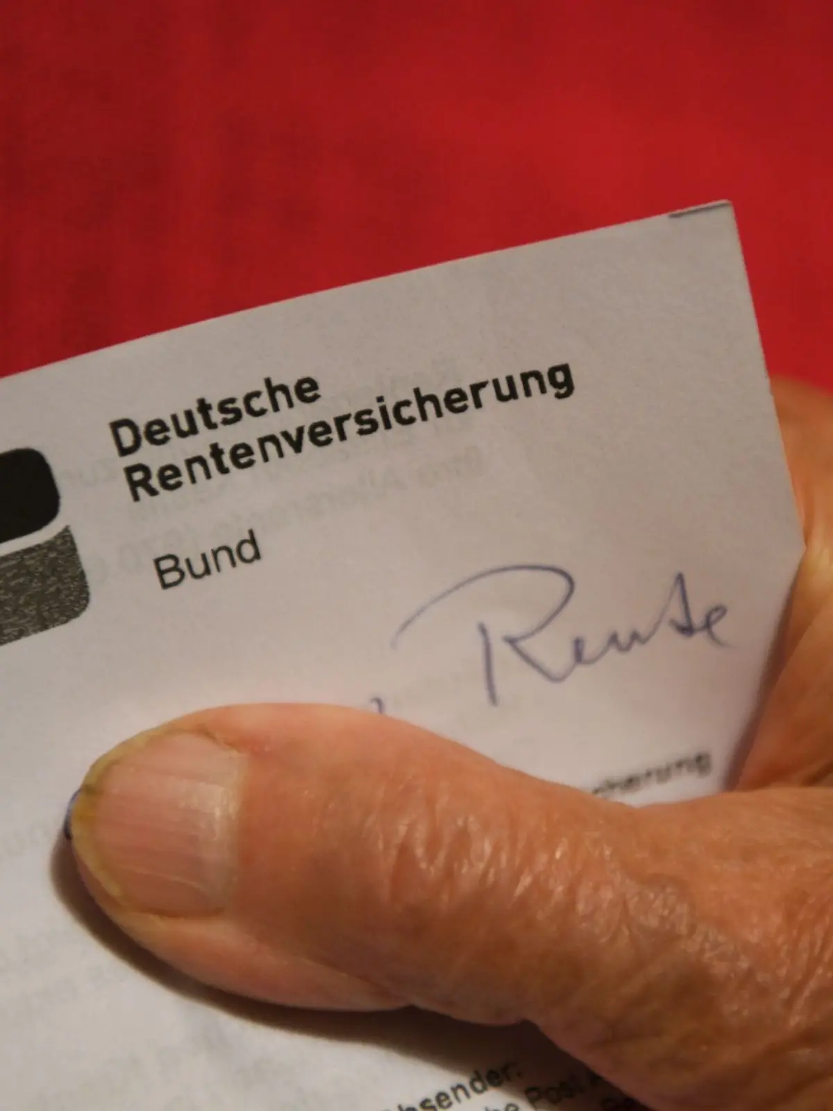 Eine Rentnerin hält ihren Rentenbescheid in der Hand.