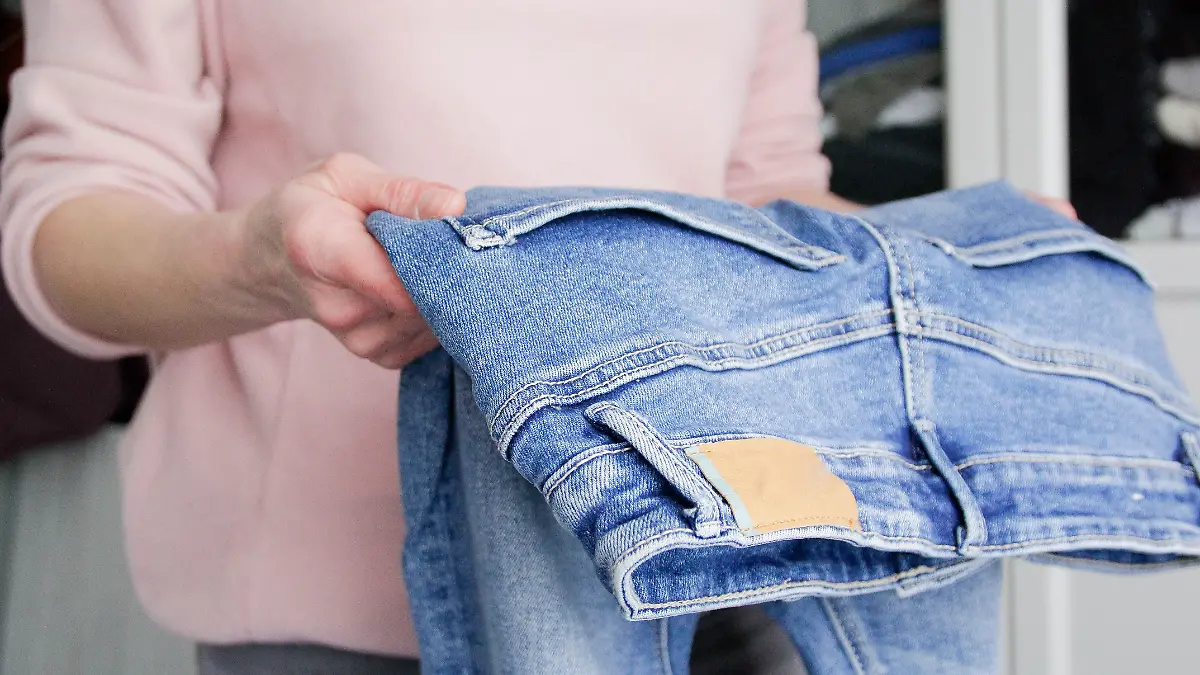 Frau trägt eine Hose in der Hand. 
