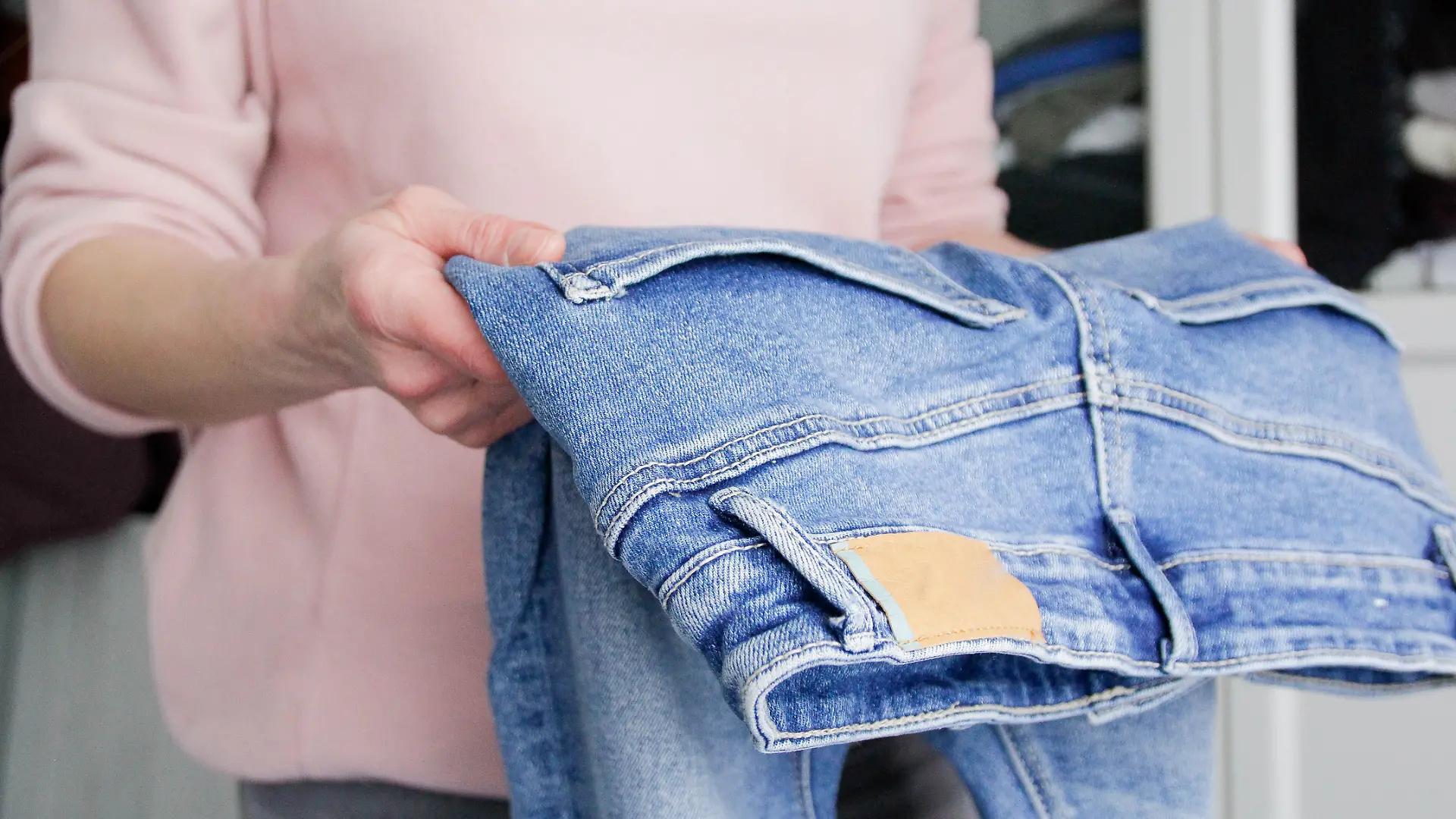 Frau trägt eine Hose in der Hand. 