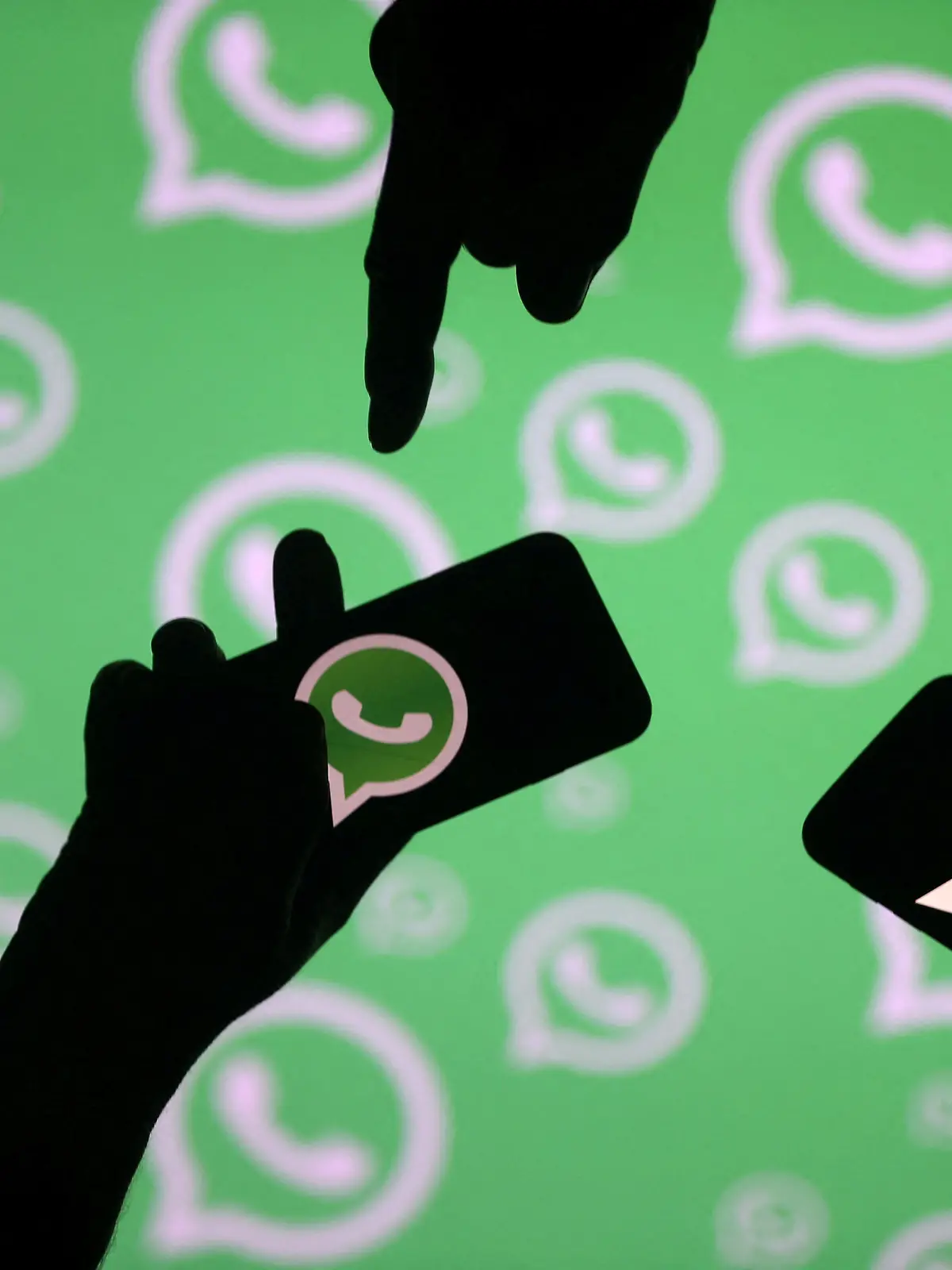 FILE PHOTO: Men pose with smartphones in front of displayed Whatsapp logo in this illustration September 14, 2017. REUTERS/Dado Ruvic/File Photo
