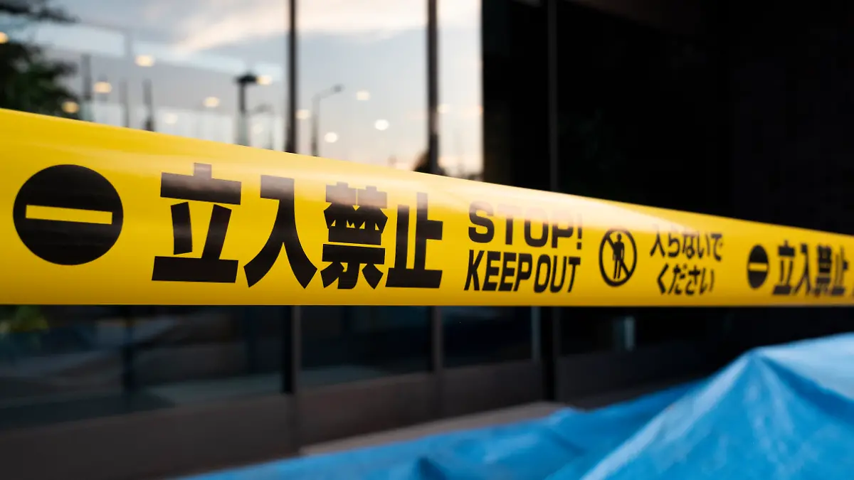 Yellow caution tape with Japanese and English languages in front of a building.