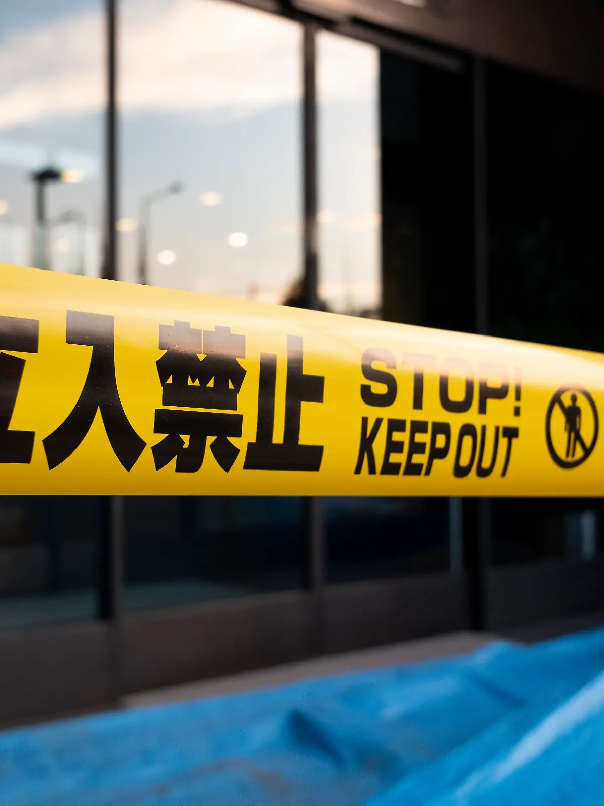Yellow caution tape with Japanese and English languages in front of a building.