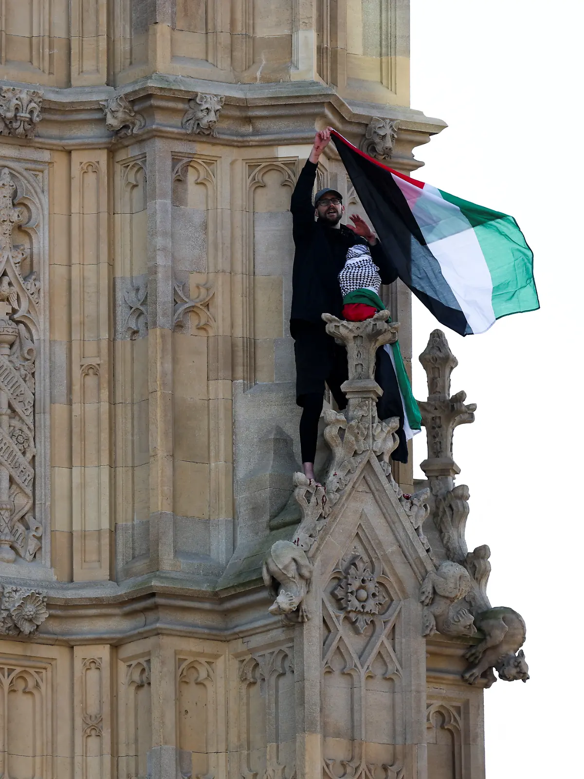 A man waves a Palestinian flag as he stands on the Elizabeth Tower, commonly known as Big Ben, next to Houses of Parliament, in London, Britain March 8, 2025. 