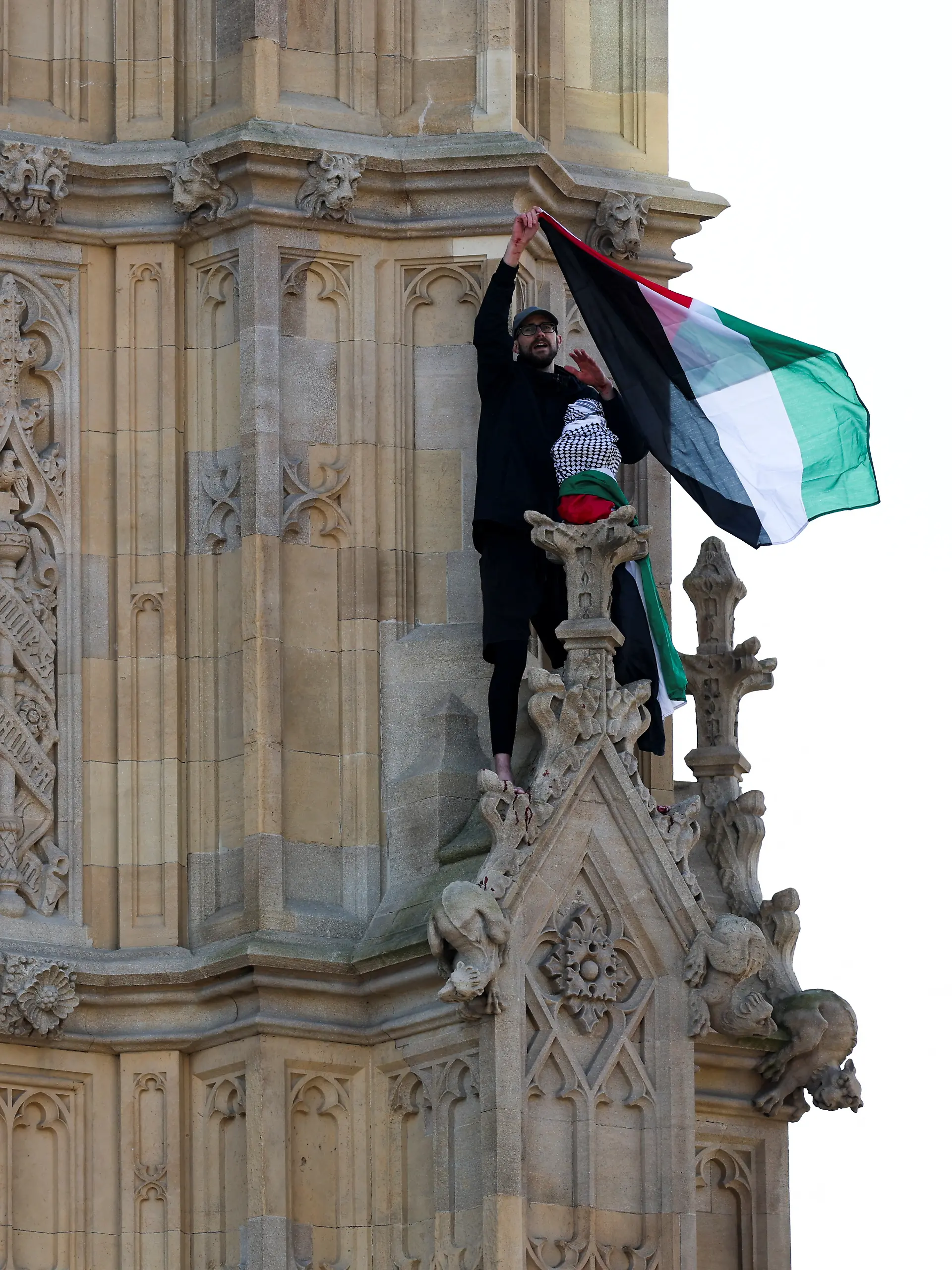 A man waves a Palestinian flag as he stands on the Elizabeth Tower, commonly known as Big Ben, next to Houses of Parliament, in London, Britain March 8, 2025. 