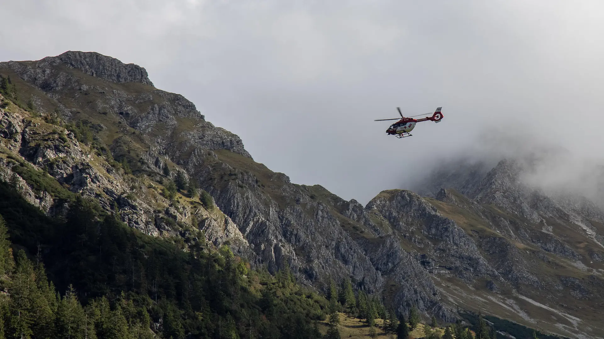 Der Rettungshubschrauber "RK2" ist in den Alpen bei Oberstdorf bei einem Bergunfall mit der Rettungswinde im Einsatz.