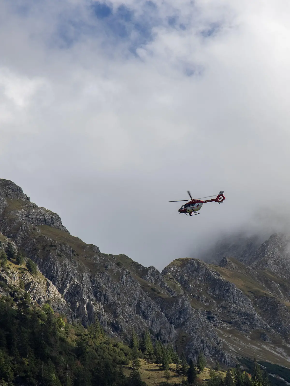 Der Rettungshubschrauber "RK2" ist in den Alpen bei Oberstdorf bei einem Bergunfall mit der Rettungswinde im Einsatz.