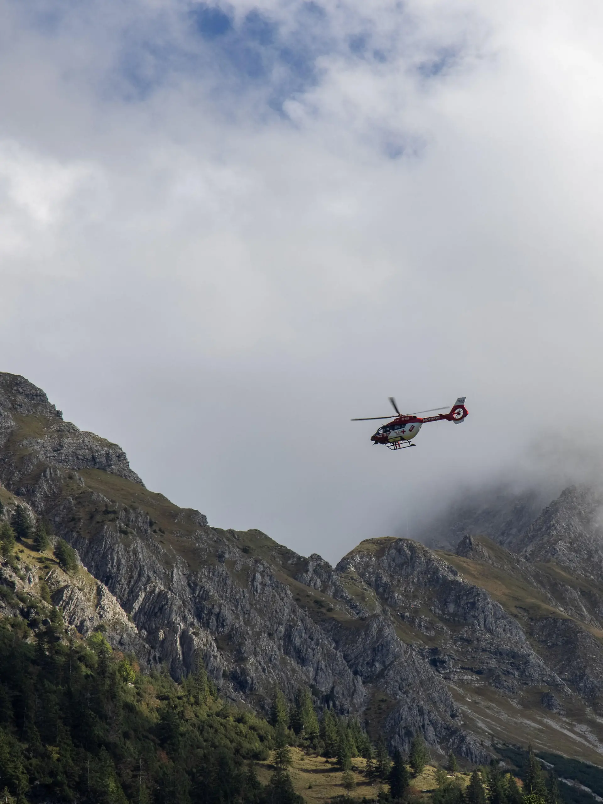 Der Rettungshubschrauber "RK2" ist in den Alpen bei Oberstdorf bei einem Bergunfall mit der Rettungswinde im Einsatz.