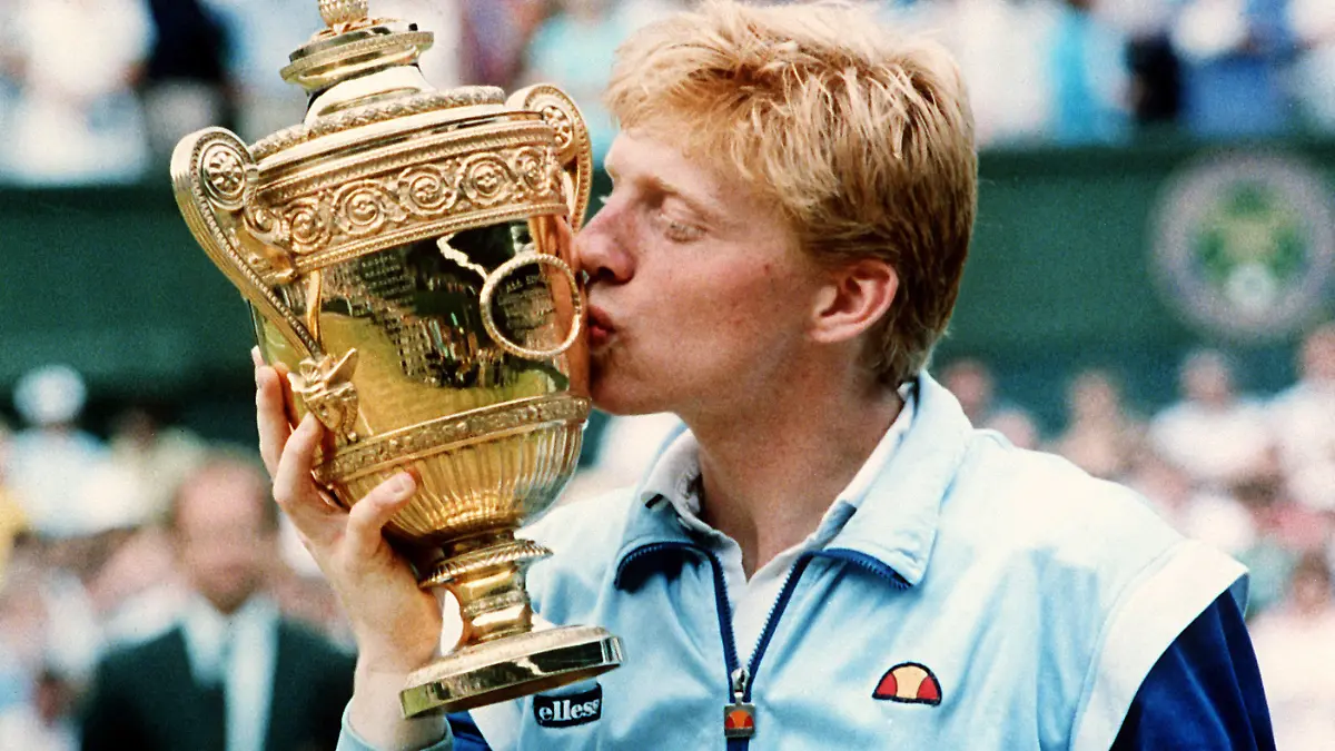 ARCHIV - 06.07.1986, Großbritannien, Wimbledon: Der damals 18-jährige Tennisspieler Boris Becker aus Leimen küsst den Pokal, nachdem er zum zweiten Mal in Folge das Herren-Einzel-Finale in Wimbledon gewonnen hat.  Der ehemalige Tennis-Star muss sich vom 21. März an bis zu drei Wochen lang vor Gericht in London dem Vorwurf stellen, er habe in seinem Insolvenzverfahren Vermögenswerte nicht ordnungsgemäß angegeben und Trophäen nicht ausgehändigt. Theoretisch könnten ihm bis zu sieben Jahre Haft drohen. (zu dpa "Boris Becker vor Gericht: Vom Tennis-Olymp auf die Anklagebank") Foto: Wolfgang Eilmes/dpa +++ dpa-Bildfunk +++
