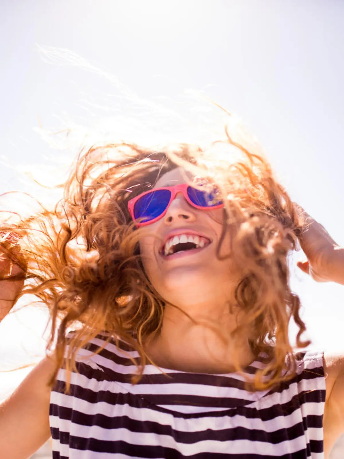 Cheerful laughing teenage girl during summer holiday on the beach