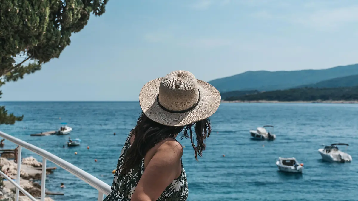 A woman leaning on a railing on the seashore in Rabac, Croatia