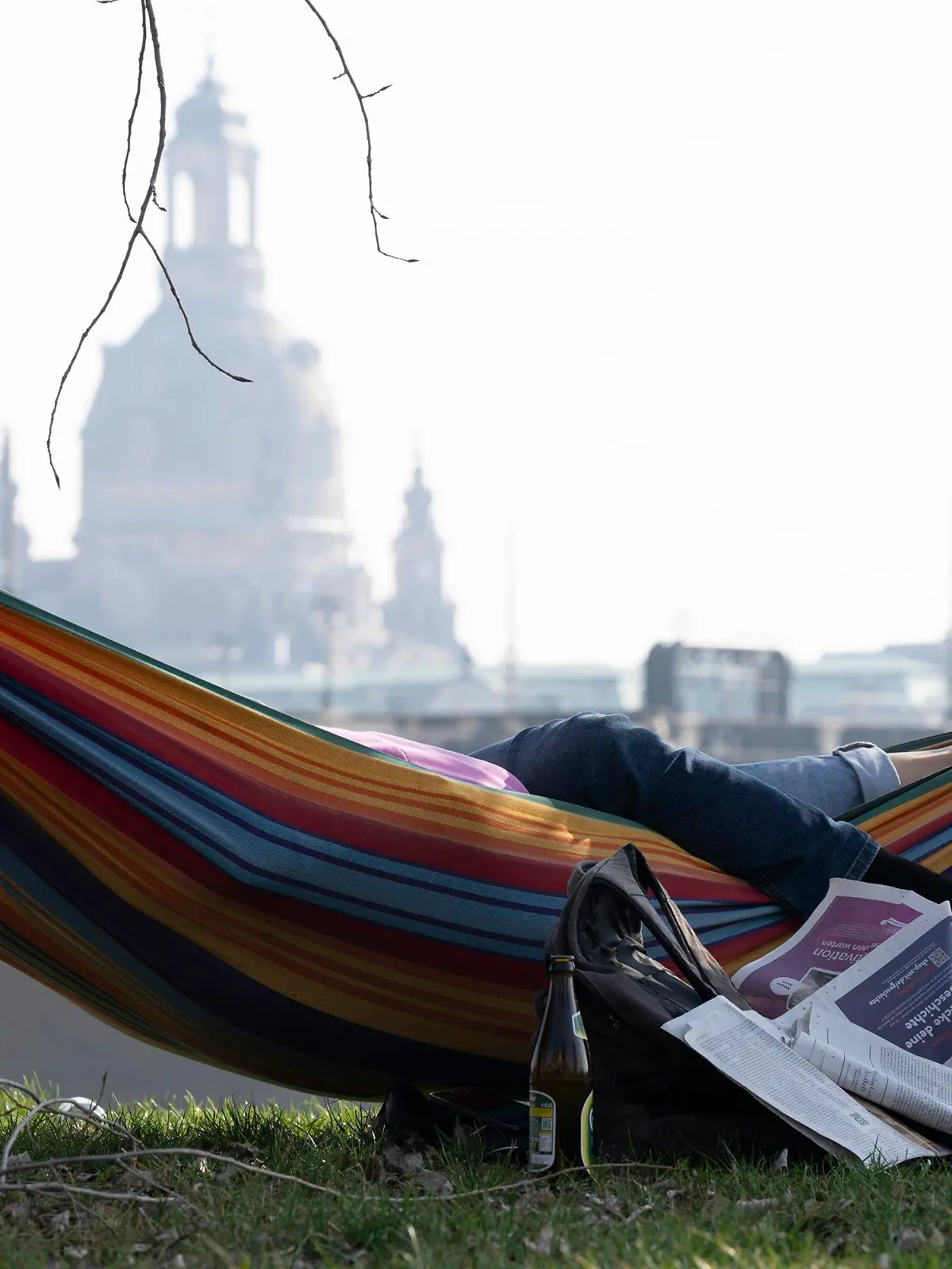 10.03.2025, Sachsen, Dresden: Erholungssuchende liegen vor der Kulisse der Frauenkirche in einer Hängematte. Foto: Sebastian Kahnert/dpa +++ dpa-Bildfunk +++