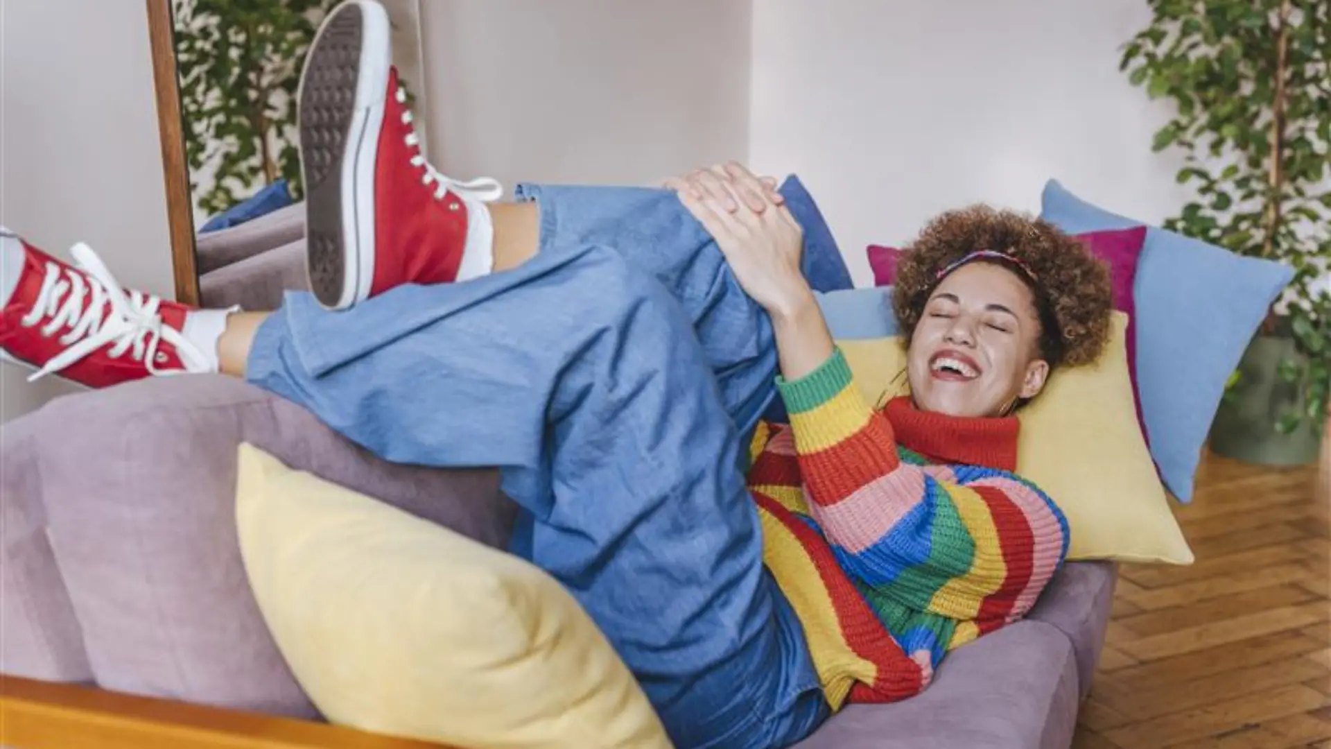 Lächelnde junge Frau auf dem Sofa zu Hause liegend