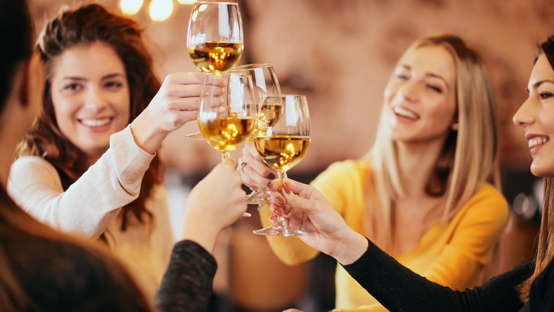 Eine weibliche Gruppe von Freunden stößt mit einem Glas Wein an.