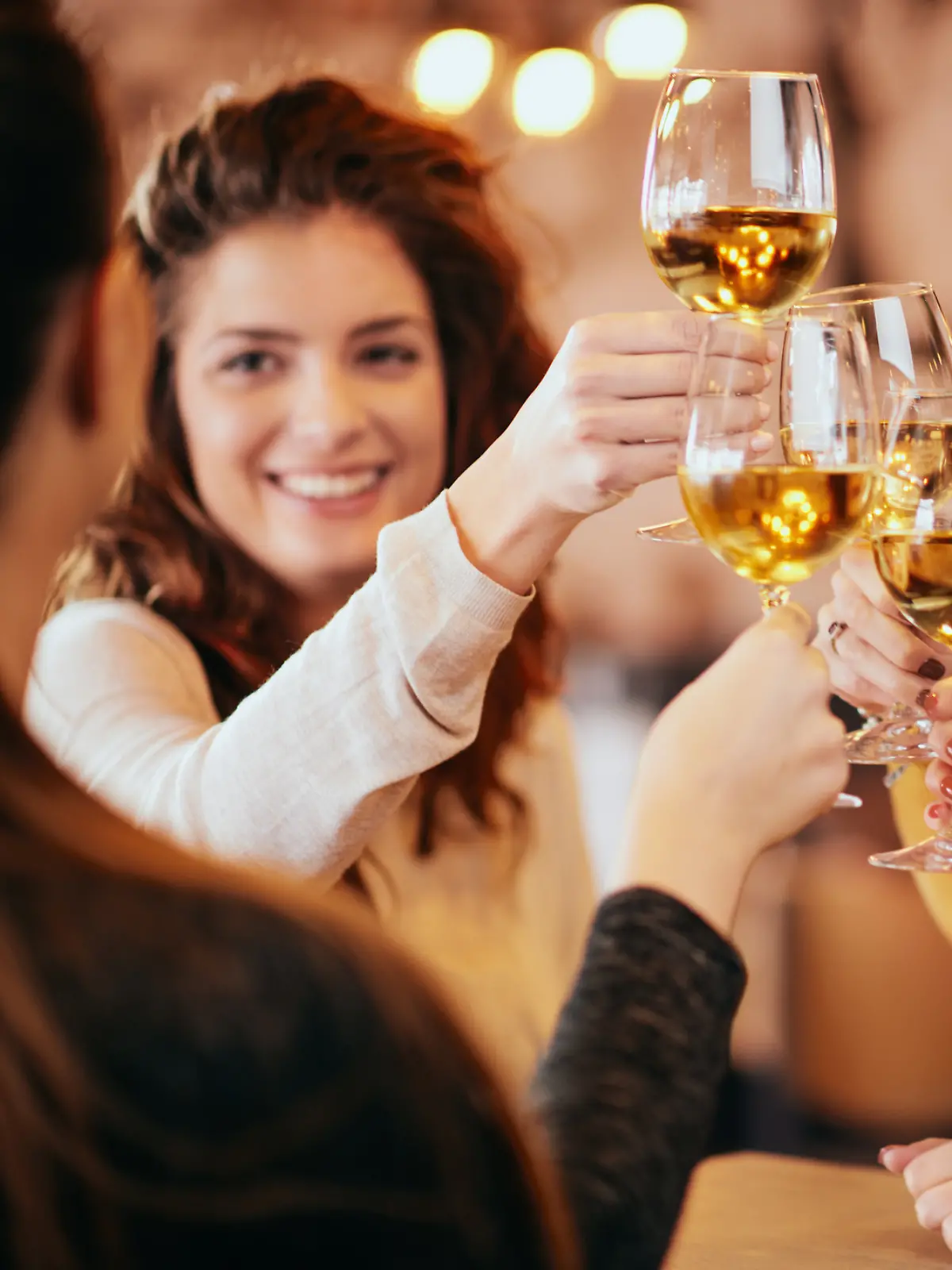 Eine weibliche Gruppe von Freunden stößt mit einem Glas Wein an.