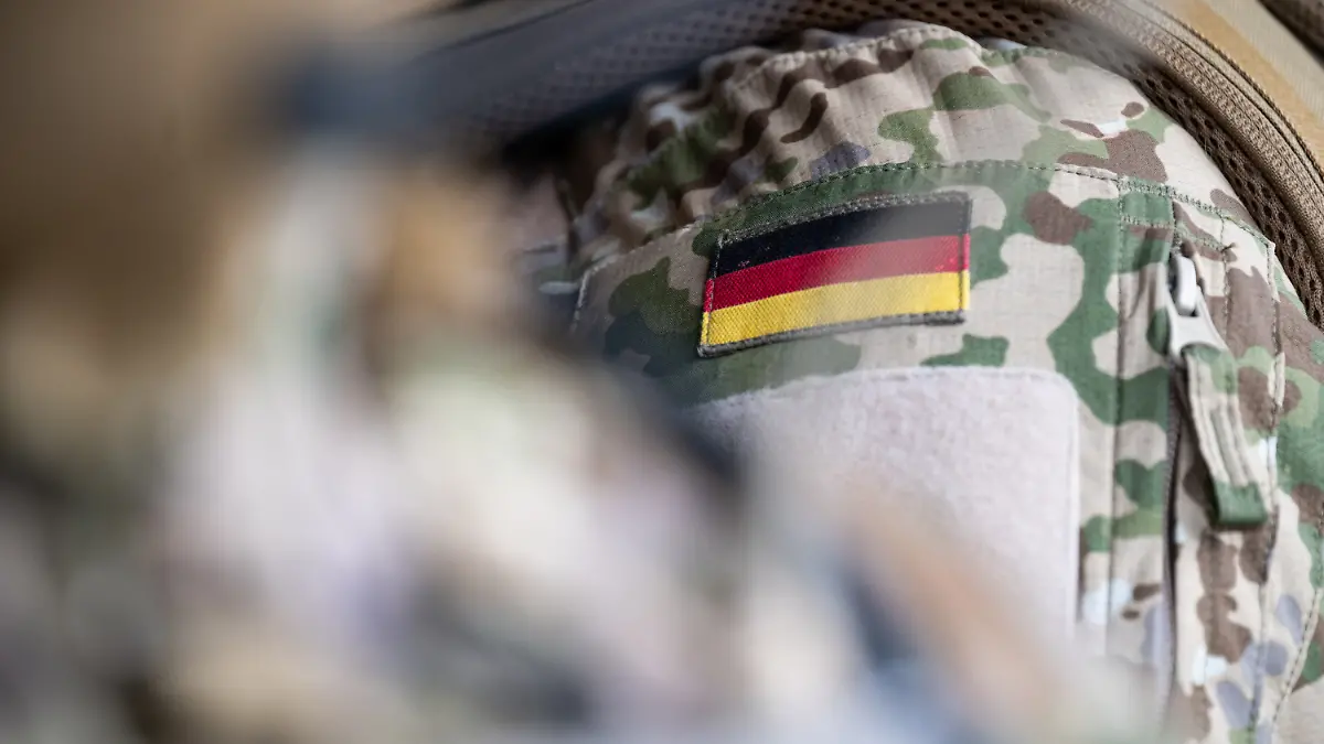 Die Bundesflagge ist an der Uniform eines Mitglieds vom Kommando Spezialkräfte (KSK) während eines Besuchs von Bundeskanzler Scholz beim KSK zu sehen.