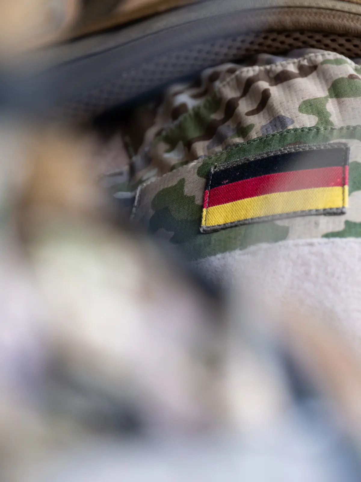 Die Bundesflagge ist an der Uniform eines Mitglieds vom Kommando Spezialkräfte (KSK) während eines Besuchs von Bundeskanzler Scholz beim KSK zu sehen.
