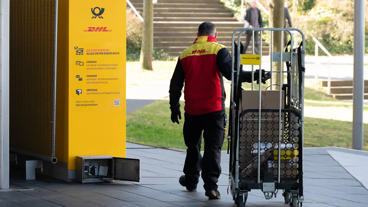Ein Zusteller, DHL-Mitarbeiter sortiert Pakete in eine Packstation