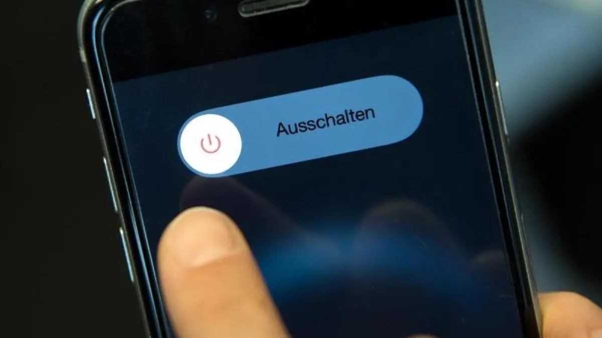 Eine Frau schaltet ihr Smartphone aus. Foto: Sven Hoppe/Archiv