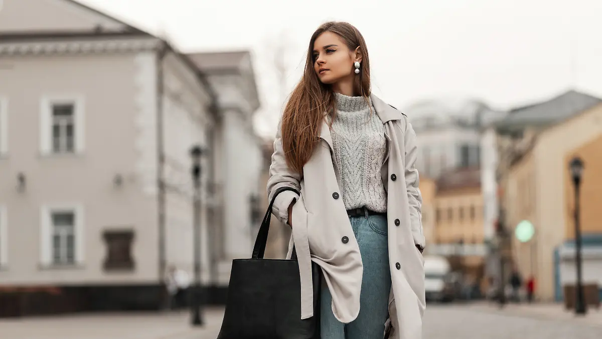 Junge Frau mit Trenchcoat und Pullover.
