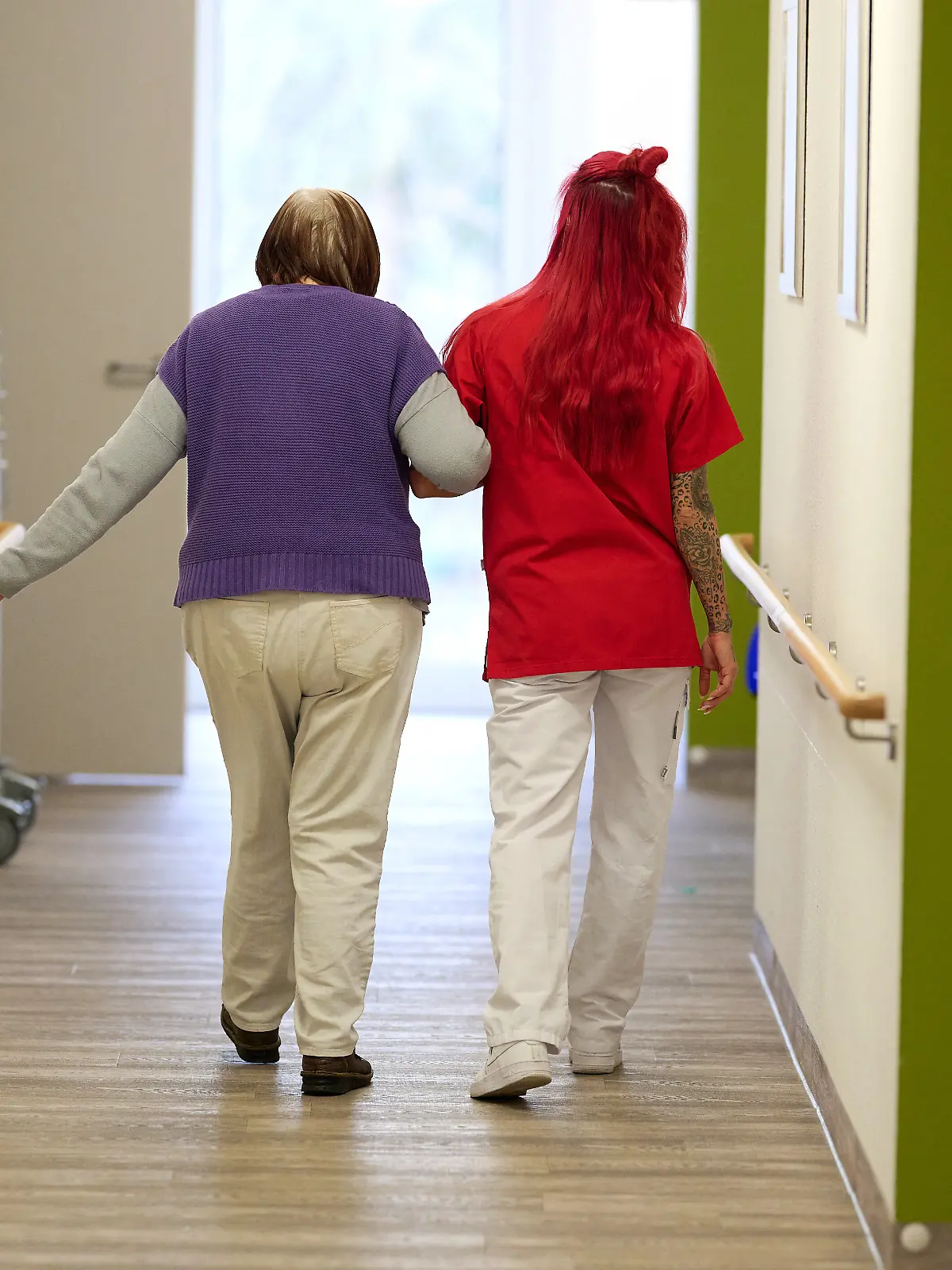 Eine Pflegekraft begleitet im DRK-Pflegezentrum Solferino eine Seniorin durch den Flur.