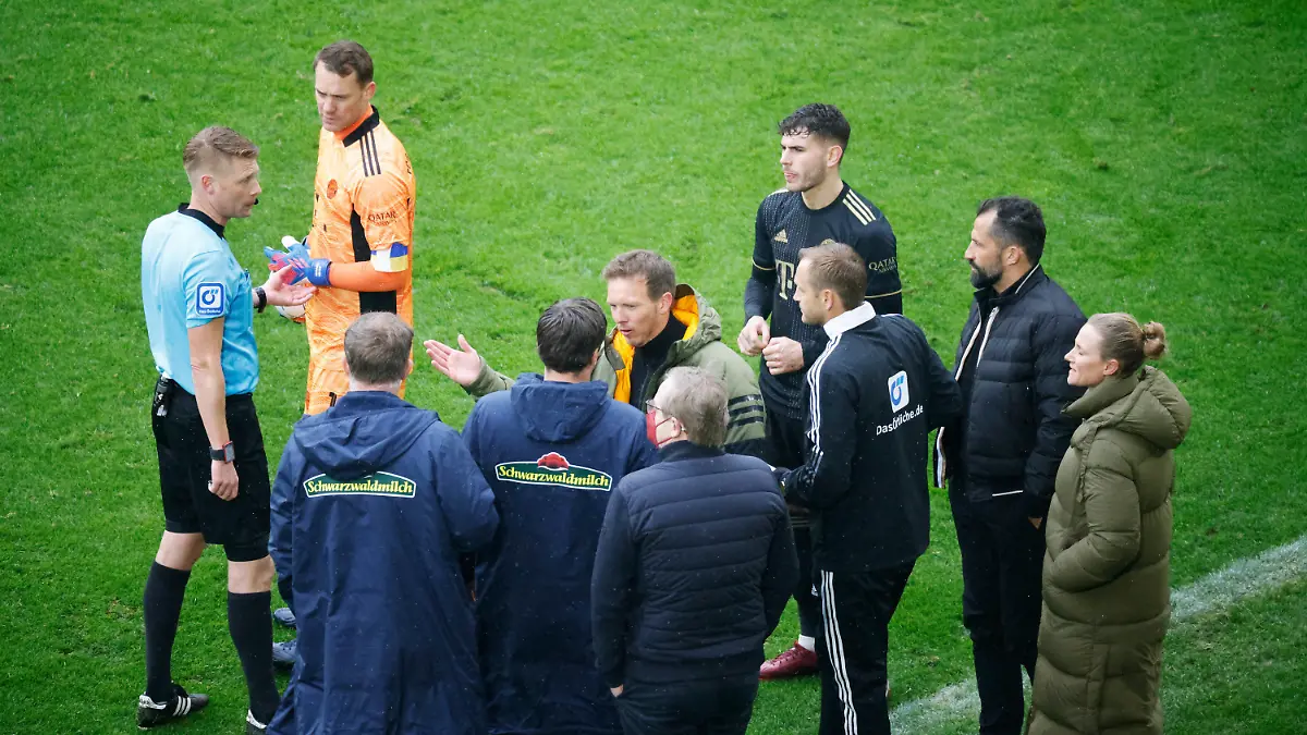 02.04.2022, Baden-Württemberg, Freiburg im Breisgau: Fußball: Bundesliga, SC Freiburg - Bayern München, 28. Spieltag, Europa-Park Stadion: Schiedsrichter Christian Dingert (l in blau) bespricht mit dem vierten Offiziellen sowie Spielern und Verantwortlichen des FC Bayern München sowie des SC Freiburg das Vorgehen. Der FC Bayern stand für rund 20 Sekunden mit einem Spieler zu viel auf dem Spielfeld. (zu dpa «Nach Bayern-Wechselfehler: Redebedarf bei DFB-Schiedsrichtern ») Foto: Philipp von Ditfurth/dpa - WICHTIGER HINWEIS: Gemäß den Vorgaben der DFL Deutsche Fußball Liga bzw. des DFB Deutscher Fußball-Bund ist es untersagt, in dem Stadion und/oder vom Spiel angefertigte Fotoaufnahmen in Form von Sequenzbildern und/oder videoähnlichen Fotostrecken zu verwerten bzw. verwerten zu lassen. +++ dpa-Bildfunk +++