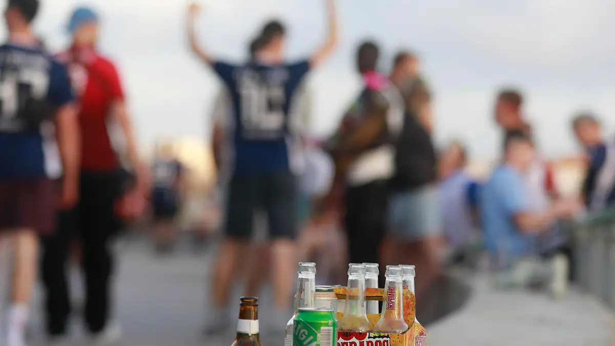 PRODUKTION - 09.06.2023, Spanien, Palma: Menschen haben sich am Abend an der Promenade am Strand von Arenal versammelt. Auf einer Balustrade stehen mehrere leere Flachen alkoholischer Getränke. Unternehmer schlagen Alarm, Nachbarn haben Angst. Am Ballermann sorgen die Partyurlauber dieses Jahr bereits lange vor Start der Hauptsaison für Ärger. (zu dpa "Sauftourismus nicht zu bremsen - Angst vor dem Sommer auf Mallorca") Foto: Clara Margais/dpa +++ dpa-Bildfunk +++