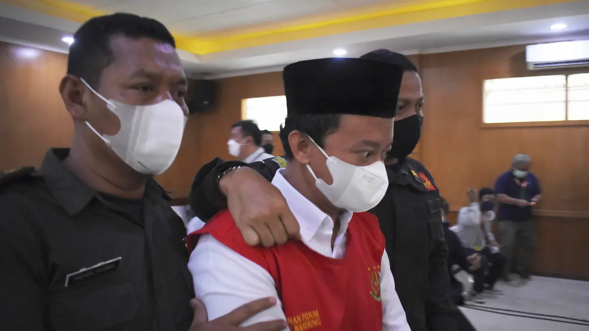 Herry Wirawan, center, the principal of a girls Islamic boarding school accused of raping his students, is escorted by security officers during a sentencing hearing at a district court in Bandung, West java, Indonesia, Tuesday, Feb. 15, 2022. The court sentenced Wirawan to life in prison for raping at least 13 students between the ages of 11 and 14 and impregnating some of them. (AP Photo/Rafi Fadh)