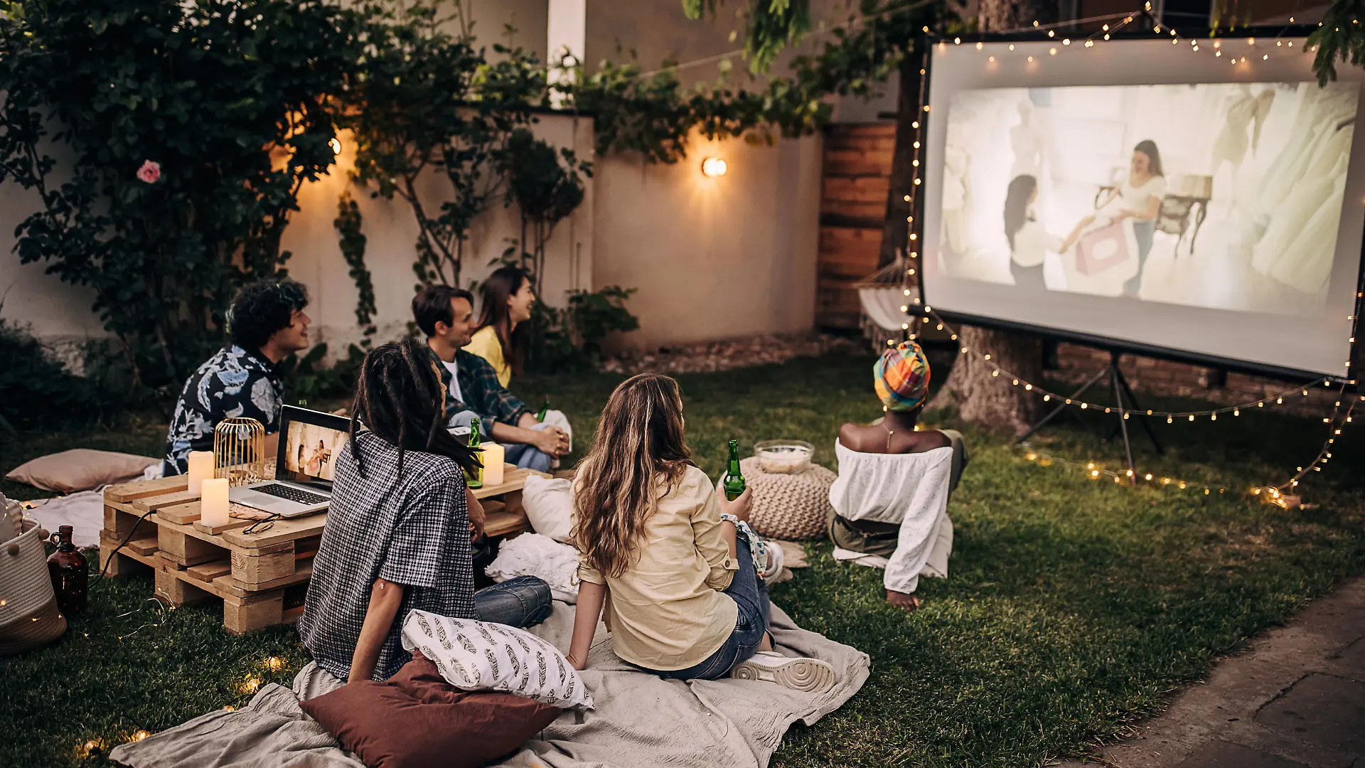 Friends watching movie on the video projector in the backyard garden