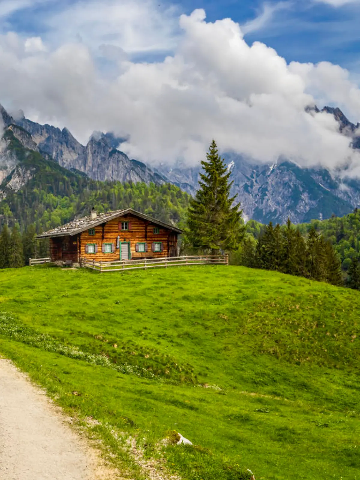 Beautiful view of scenic mountain landscape in the Alps with traditional mountain chalet and fresh green meadows