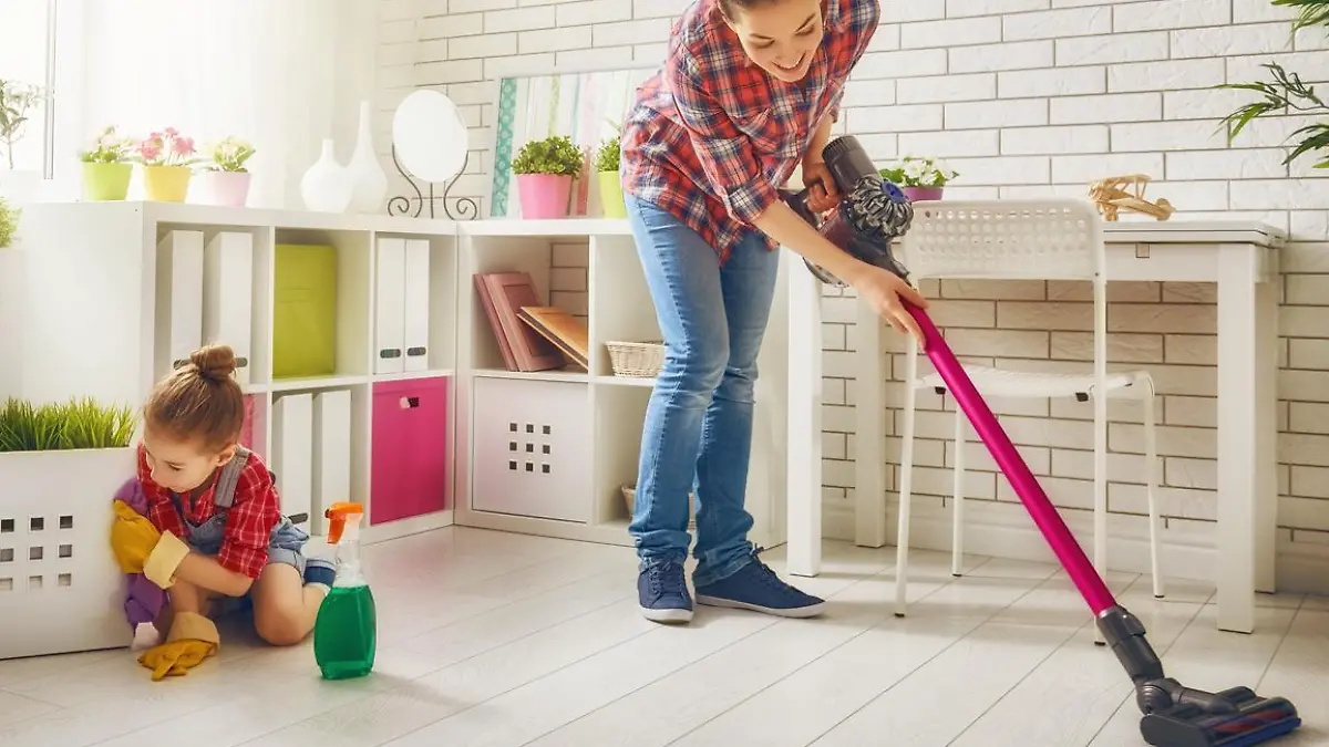 Frau saugt mit einem kabellosen Staubsauger und dem Sofa.