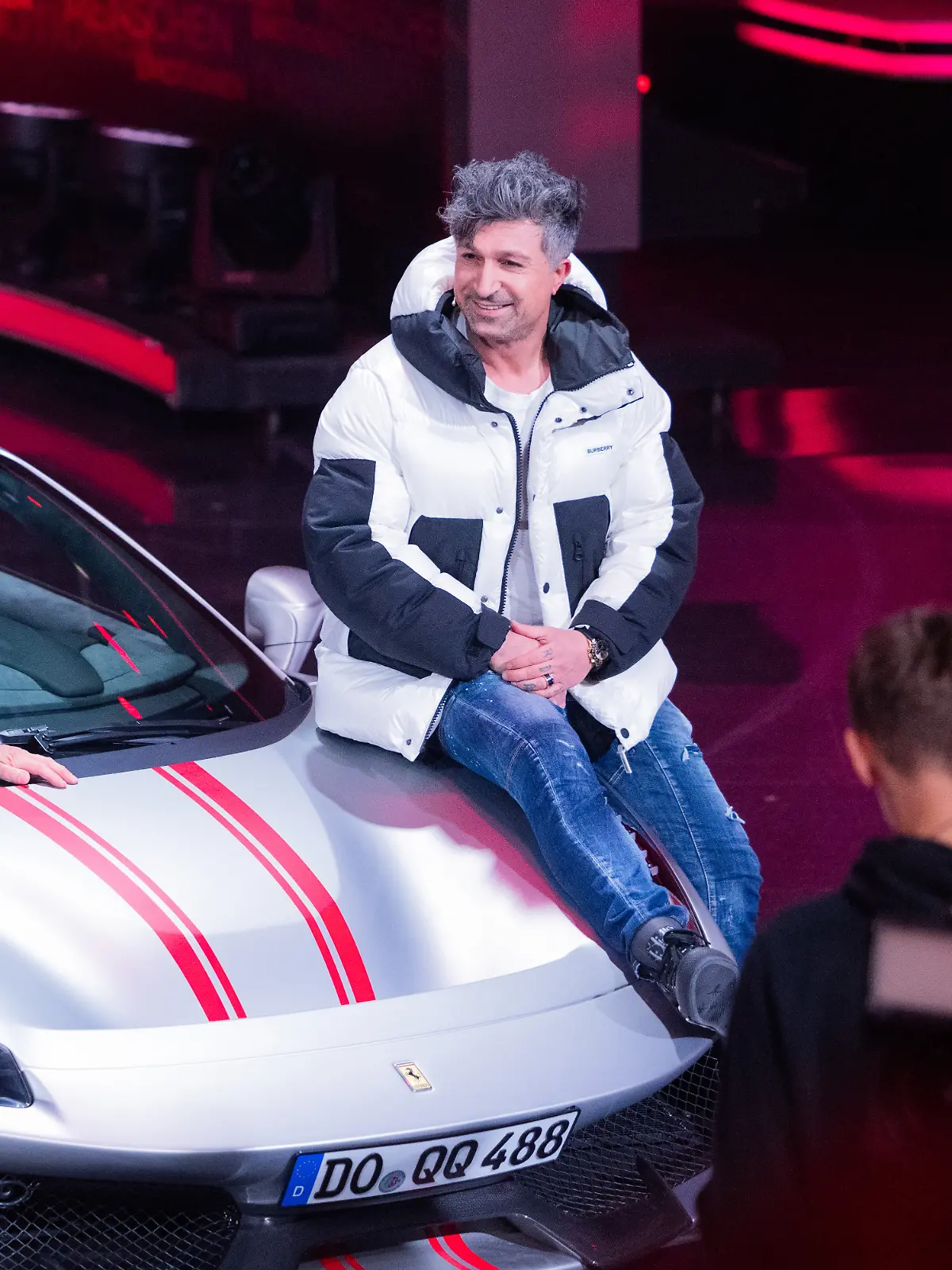 Thomas Gottschalk (l), Moderator, und Lotto-Millionär Kürsat Yildirim alias „Chico” sitzen auf einem Ferrari beim RTL-Jahresrückblick „Menschen, Bilder, Emotionen 2022” im Studio.