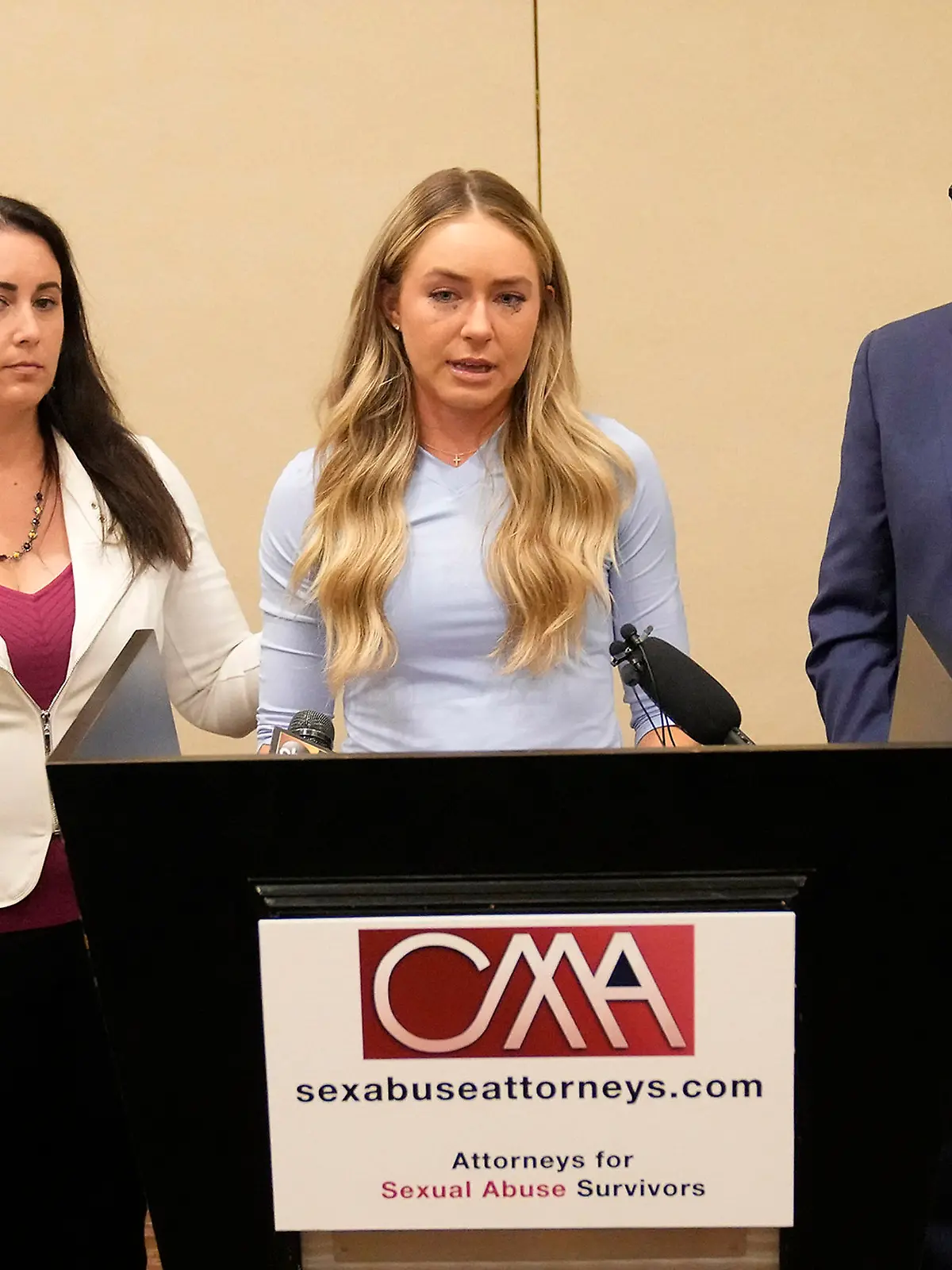 Tennis player Kylie McKenzie, middle, with her attorney Robert Allard, right, and victim advocate Jancy Thompson, left, speaks to reporters at a news conference in Phoenix Tuesday, March 29, 2022. McKenzie alleges in a lawsuit that the U.S. Tennis Association failed to protect her from a coach who she says sexually abused her when she was 19. The Associated Press generally doesn't name alleged sexual assault victims but McKenzie agreed to let her identity be known in coverage of her lawsuit. (Michael Chow/The Arizona Republic via AP)