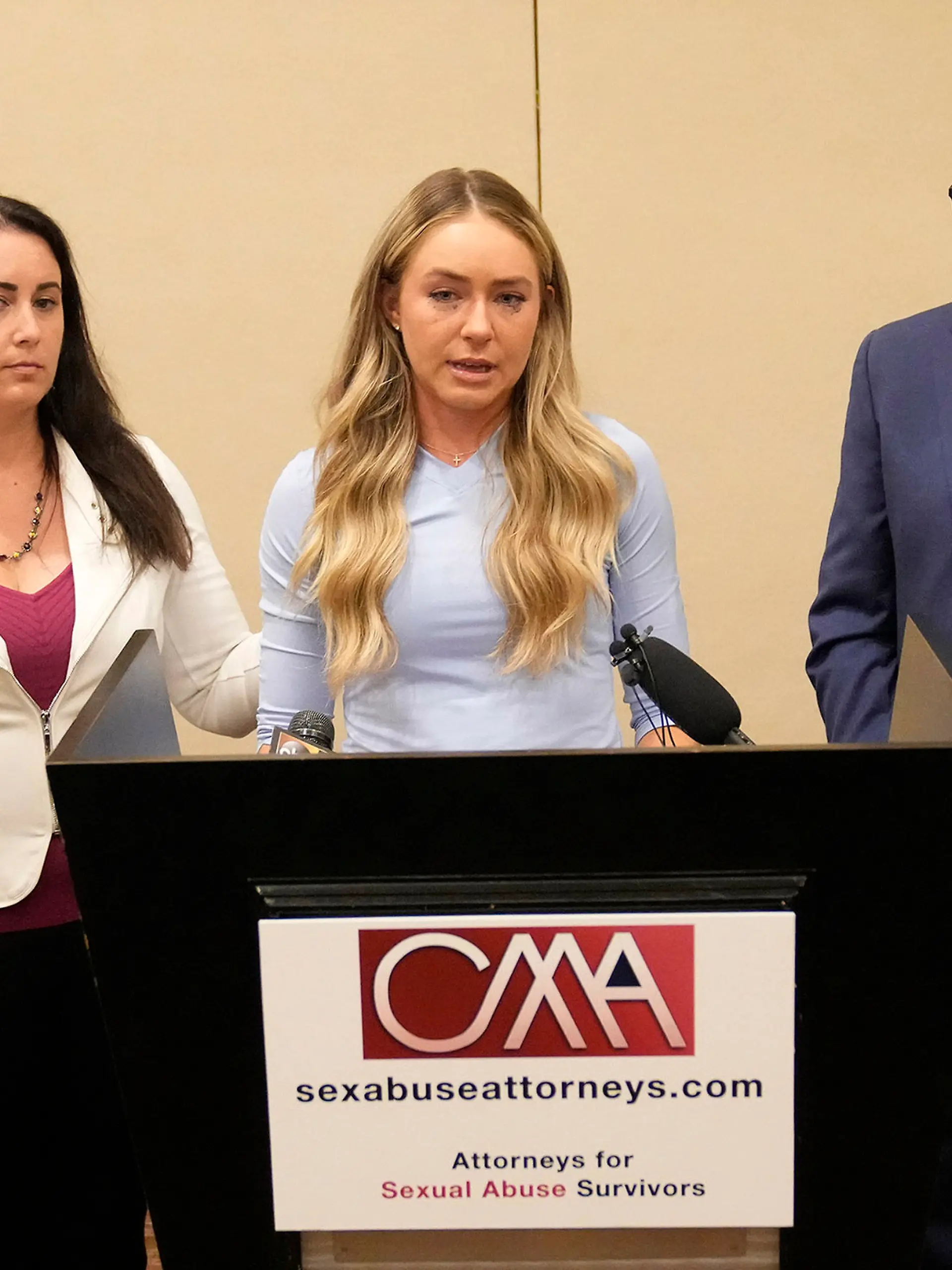 Tennis player Kylie McKenzie, middle, with her attorney Robert Allard, right, and victim advocate Jancy Thompson, left, speaks to reporters at a news conference in Phoenix Tuesday, March 29, 2022. McKenzie alleges in a lawsuit that the U.S. Tennis Association failed to protect her from a coach who she says sexually abused her when she was 19. The Associated Press generally doesn't name alleged sexual assault victims but McKenzie agreed to let her identity be known in coverage of her lawsuit. (Michael Chow/The Arizona Republic via AP)