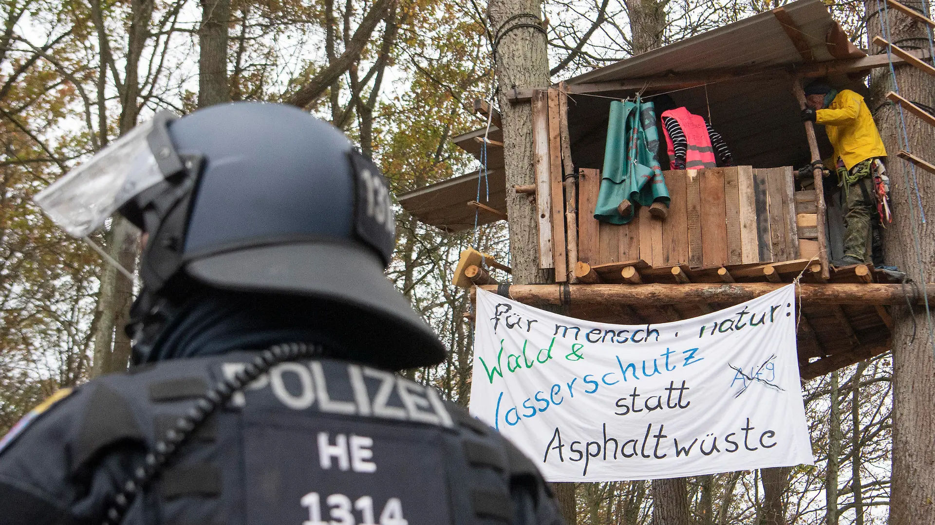 ARCHIV - 10.11.2020, Hessen, Niederklein: Ein Polizist steht im Dannenröder Forst vor einem Baumhaus, in dem sich Aktivisten aufhalten. Die Demonstranten protestierten gegen weitere Rodungsarbeiten für den Weiterbau der Autobahn 49. (zu dpa «Land zahlt Polizei mit knapp 15 Millionen Euro Überstunden aus») Foto: Helmut Fricke/dpa +++ dpa-Bildfunk +++