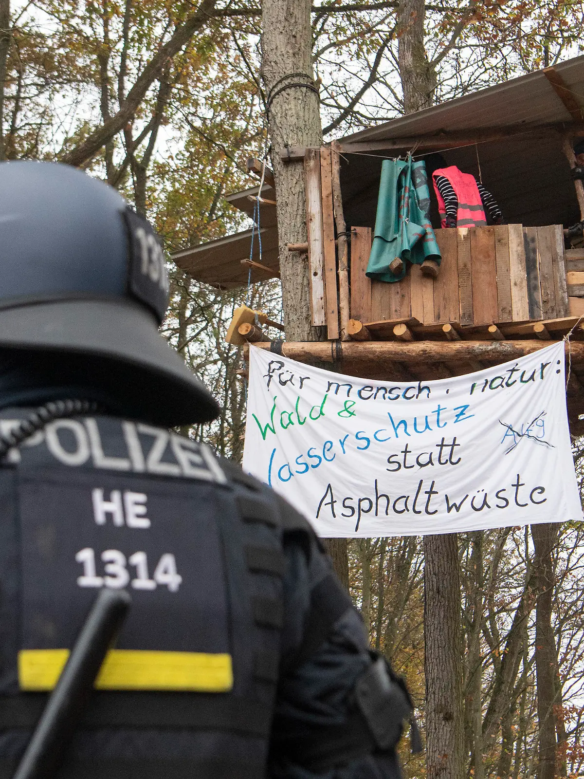 ARCHIV - 10.11.2020, Hessen, Niederklein: Ein Polizist steht im Dannenröder Forst vor einem Baumhaus, in dem sich Aktivisten aufhalten. Die Demonstranten protestierten gegen weitere Rodungsarbeiten für den Weiterbau der Autobahn 49.     (zu dpa «Land zahlt Polizei mit knapp 15 Millionen Euro Überstunden aus») Foto: Helmut Fricke/dpa +++ dpa-Bildfunk +++