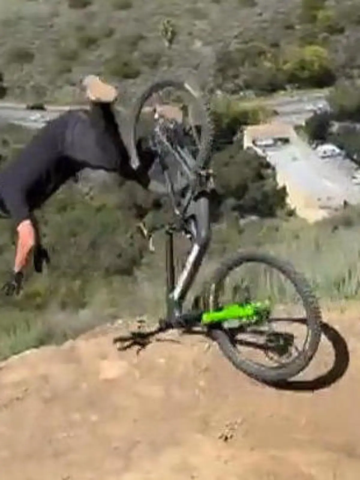 Der Moment, indem der Mountainbiker gerade über den Lenker seines Rads die Klippe hinunterstürzt.