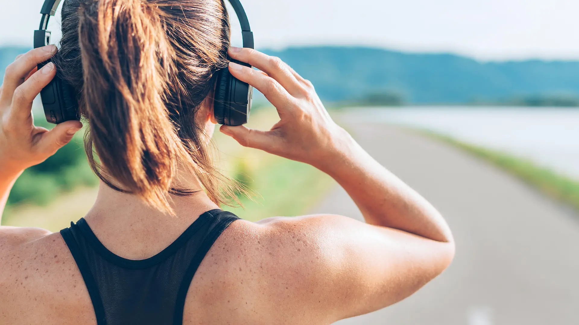 Close up image of teenager adjusting  wireless headphones before starting jogging and listening to music