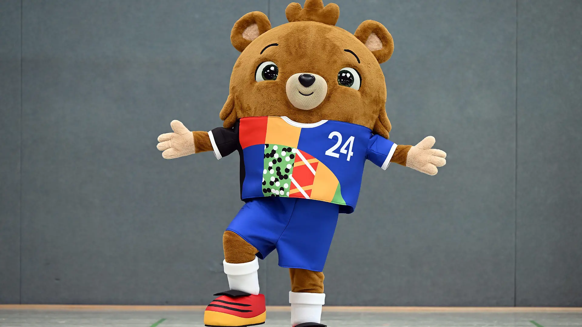 20.06.2023, Nordrhein-Westfalen, Gelsenkirchen: Fußball: EM 2024, Vorstellung des offiziellen Maskottchens. Das noch namenlose Maskottchen steht in einer Sporthalle. Ein putziger kleiner Bär - mit Hose. Die Europäische Fußball-Union UEFA hat am Dienstag das Maskottchen für die EM 2024 in Deutschland vorgestellt. Foto: Federico Gambarini/dpa +++ dpa-Bildfunk +++