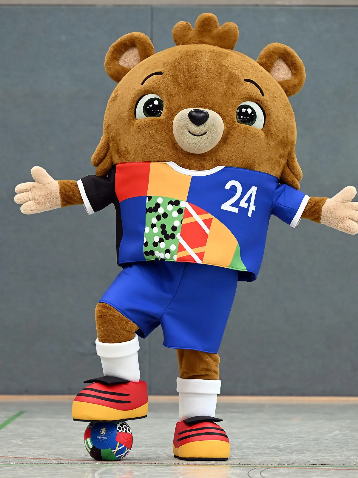 20.06.2023, Nordrhein-Westfalen, Gelsenkirchen: Fußball: EM 2024, Vorstellung des offiziellen Maskottchens. Das noch namenlose Maskottchen steht in einer Sporthalle. Ein putziger kleiner Bär - mit Hose. Die Europäische Fußball-Union UEFA hat am Dienstag das Maskottchen für die EM 2024 in Deutschland vorgestellt. Foto: Federico Gambarini/dpa +++ dpa-Bildfunk +++