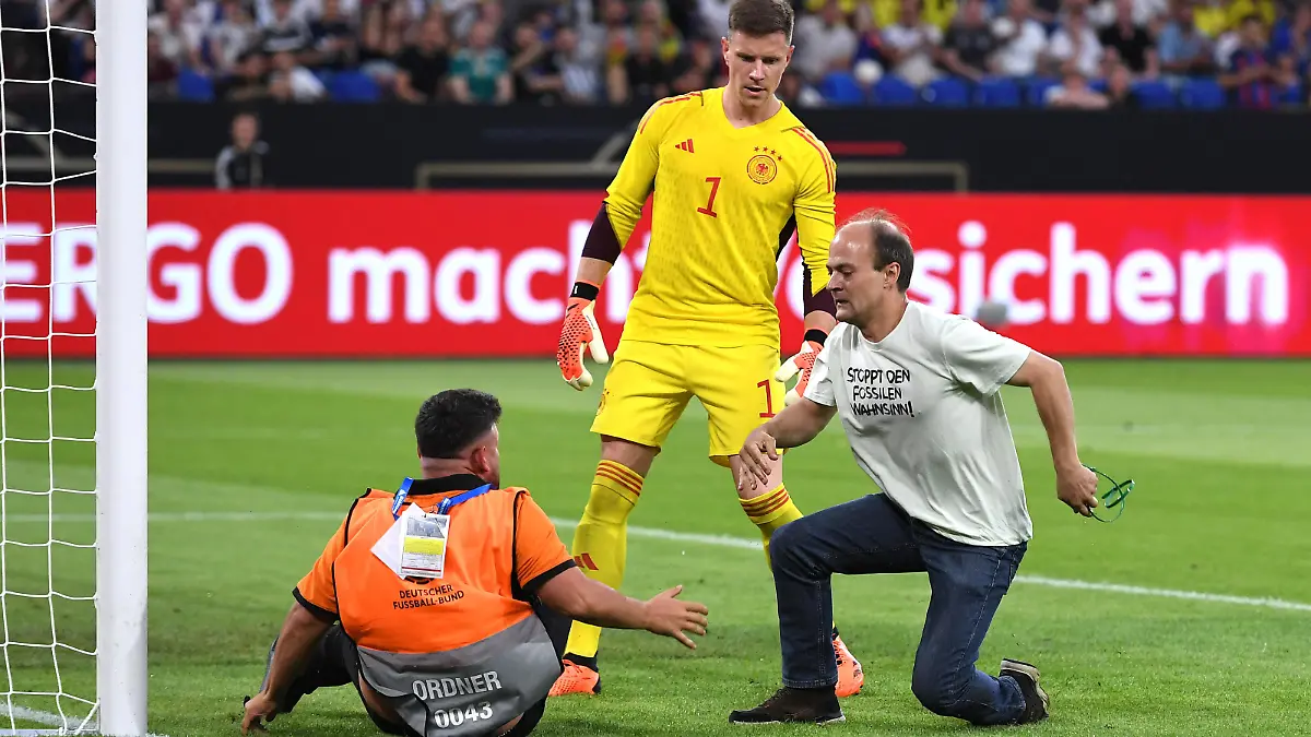 Fußball Länderspiel Deutschland - Kolumbien am 20.06.2023 in der Arena auf Schalke in Gelsenkirchen Aktivisten / Klimaktivisten stürmen auf das Spielfeld und wollen sich am Torpfosten festbinden Ordner und Marc-Andre ter Stegen Deutschland halten diese davon ab T-Shirt mit der Aufschrift: Stoppt den Fossilen Wahnsinn DFB regulations prohibit any use of photographs as image sequences and/or quasi-video. *** Soccer international match Germany Colombia on 20 06 2023 in the arena on Schalke in Gelsenkirchen activists climate activists rush onto the pitch and want to tie themselves to the goal post stewards and Marc Andre ter Stegen Germany stop them T shirt with the inscription Stop the Fossil Madness DFB regulations prohibit any use of photographs as image sequences and or quasi video xHDx