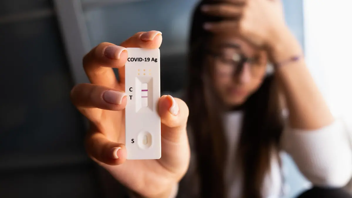 Desperate young woman holding positive result of self home test. Corona virus - Covid-19 rapid test. Young teenager girl.