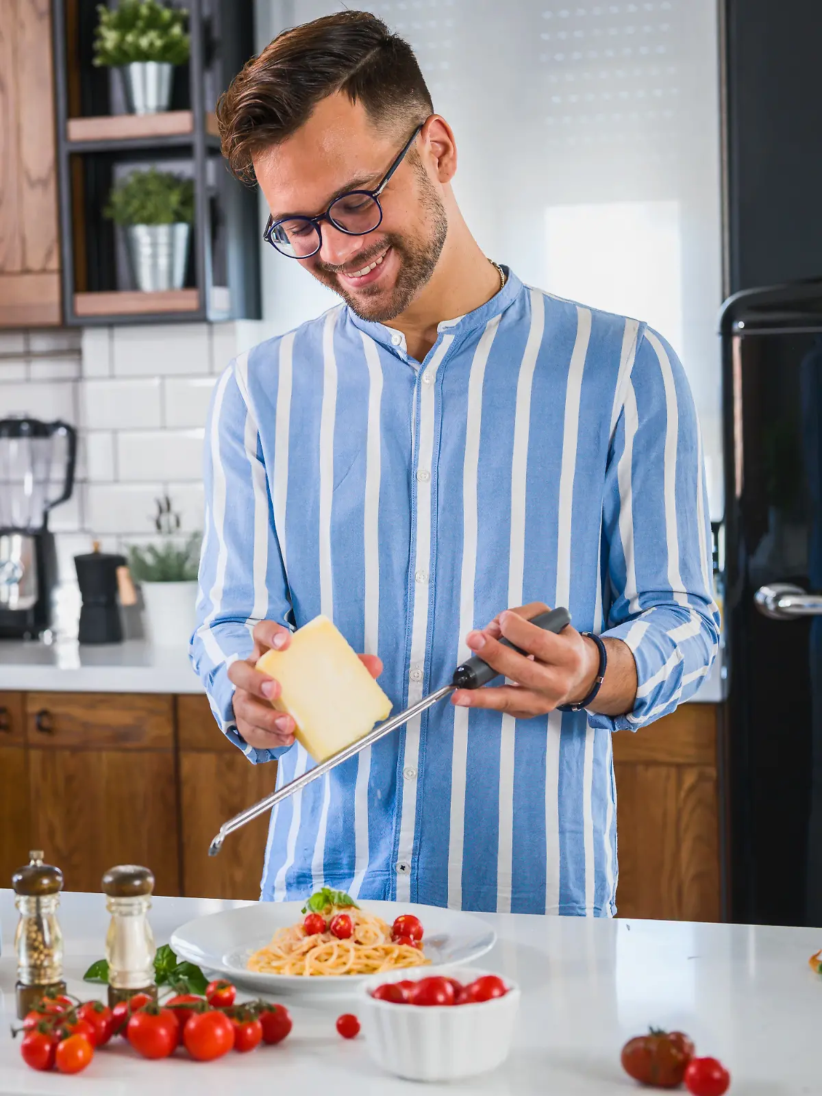 Ein Mann reibt mit einer Käsereibe Käse über seine Pasta.