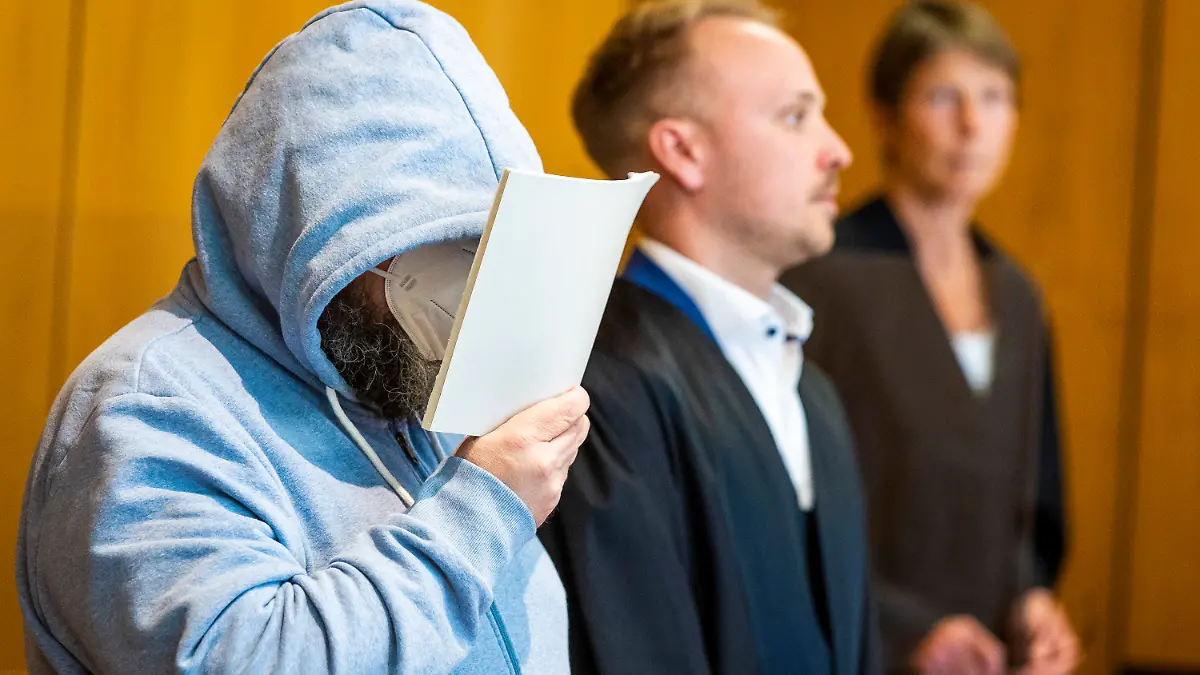 19.06.2023, Niedersachsen, Hildesheim: Der Angeklagte (l) steht beim Prozessauftakt wegen teils schweren sexuellen Missbrauchs von Kindern neben seinem Verteidiger Jonas Meese (M) in einem Saal des Landgerichts Hildesheim. Dem Angeklagten wird vorgeworfen, sich gegenüber Eltern als vertrauenswürdige Aufsichtsperson ausgegeben und dann in seiner Wohnung insgesamt 16 Straftaten begangen zu haben. Die betroffenen Kinder sollen nach Gerichtsangaben etwa zwischen fünf und zwölf Jahre alt gewesen sein. Foto: Moritz Frankenberg/dpa +++ dpa-Bildfunk +++